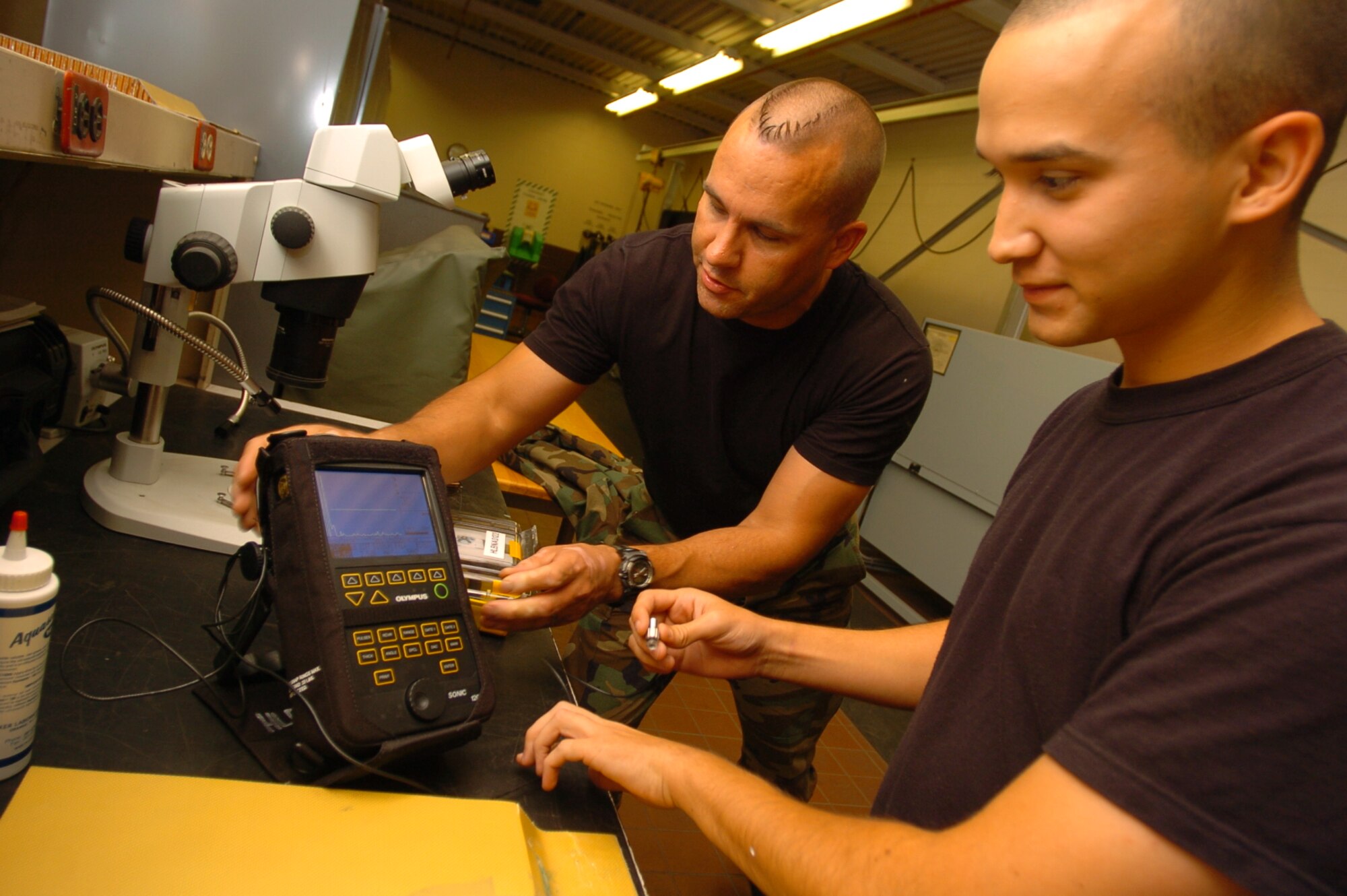 Airman 1st Class James Watts, NDI inspector at the 15th Maintenance Squadron and Tech. Sgt. Stan Rothfuss, a reservist from McChord AFB. Wa. Inspect an airplane part for cracks and damage. They are using sonogram technology to detect damage to the composite material that makes up a C-17. Photo by Angela Elbern.