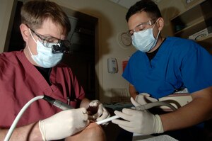Maj. Thomas Riley, 437th Medical Group general dentist, fixes a chipped tooth on Senior Airman Matthew Anderson, 437 MDG bioenvironmental engineering technician, while assisted by Staff Sgt. Alex Garcia, 437 MDG dental assistant.  (U.S. Air Force photo/Staff Sgt. April Quintanilla)