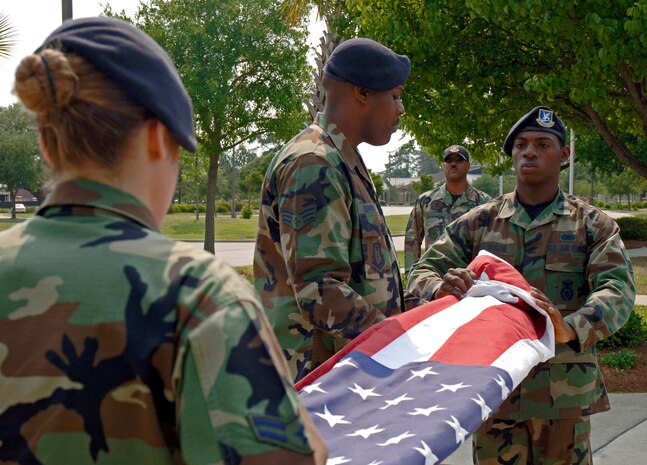 Airman 1st Class Cristy Cross (left), Senior Airman Terrence Bowers (center) and Airman 1st Class Kenneth Taylor (right), 437th Security Forces Squadron, fold the flag during a formal retreat ceremony here May 11 as part of National Police Week. (U.S. Air Force photo/Staff Sgt. Marie Cassetty)
