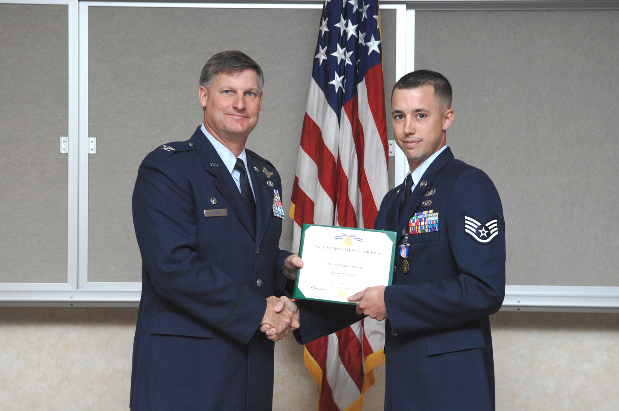 Col. Michael Bartley awards Staff Sgt. Scott White with the U.S Army Soldier's Medal May 10 at Nellis Air Force Base, Nev. Sergeant White is an explosive ordnance disposal technician assigned to the 99th Civil Engineer Squadron's EOD Flight. Colonel Bartley is the 99th Air Base Wing commander. (U.S Air Force photo/Airman 1st Class Nadine Barclay)