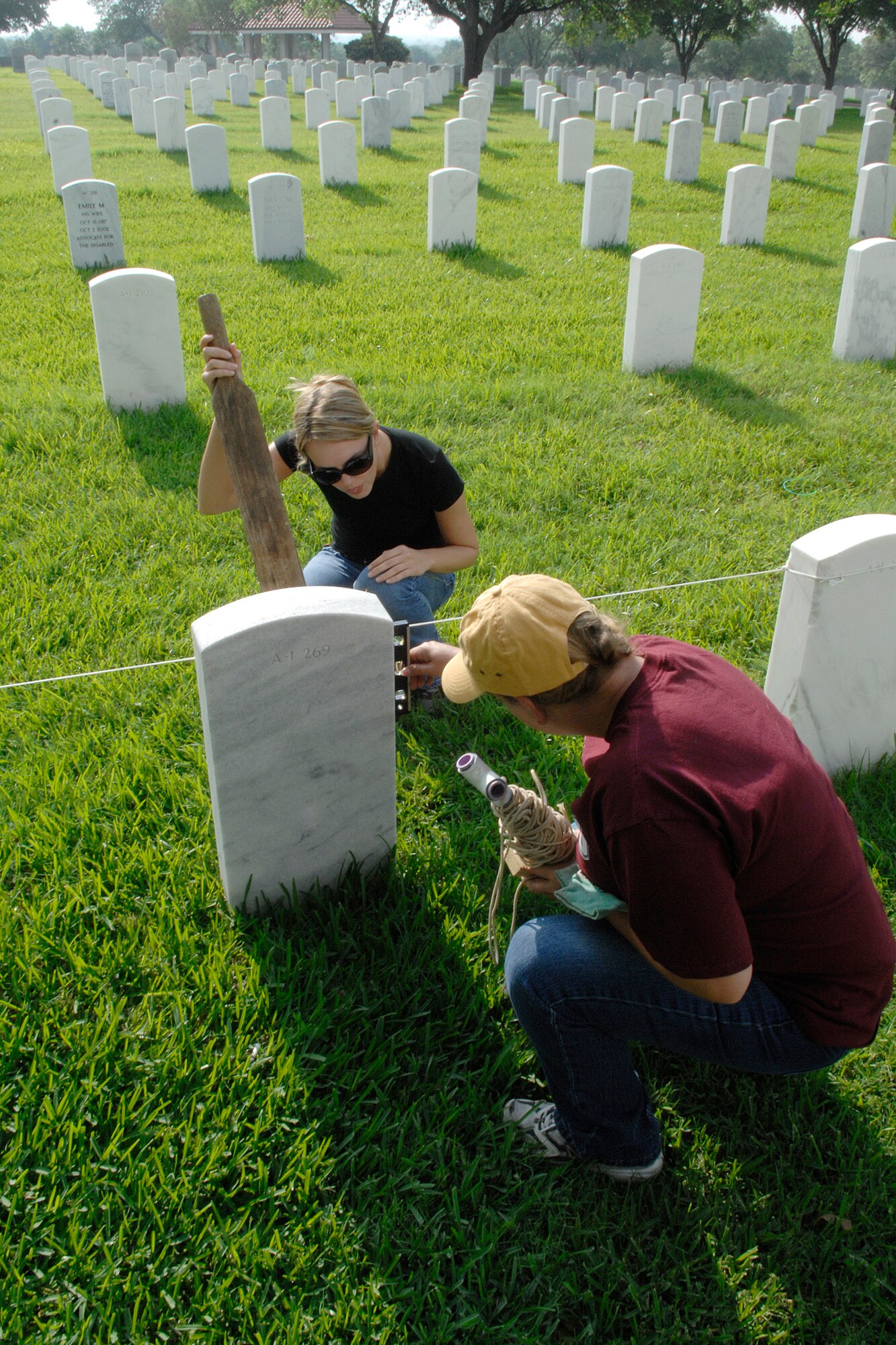 Senior Airman Lana Mills, left, and Tech. Sgt. Stacy Simon straighten headstones May 15 at the Fort Sam Houston National Cemetery in San Antonio. This process aligns and straightens all the headstones and prepares the cemetery for funerals and the upcoming Memorial Day weekend. Airmen assigned to the Air Force News Agency in San Antonio spent the day adjusting the headstones. (U.S. Air Force photo/Tech. Sgt. Larry A. Simmons)