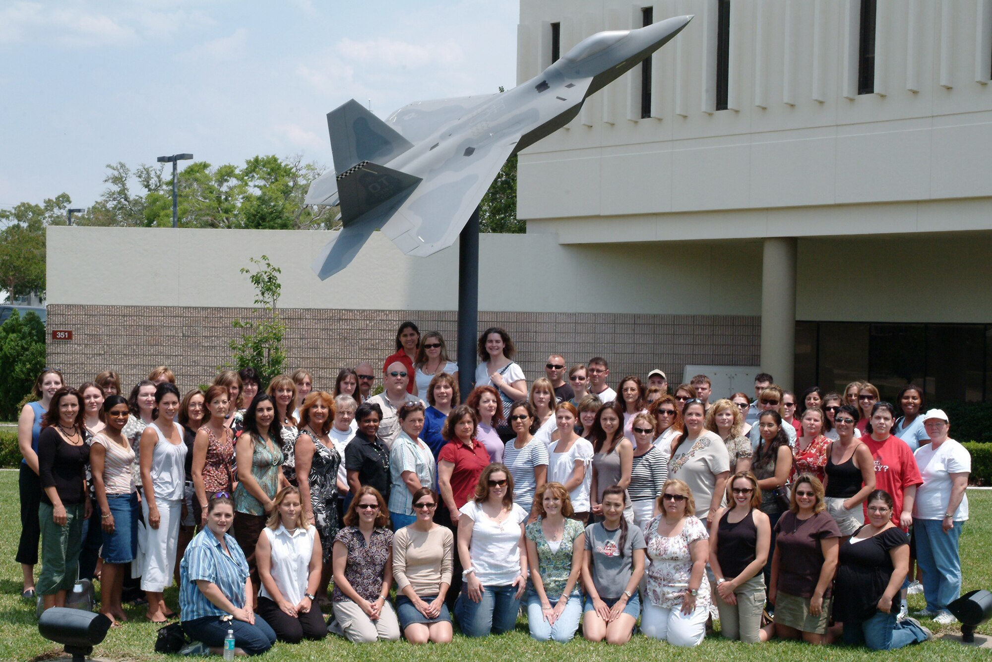 EGLIN AFB -- More than 70 wing spouses gathered in front of the F-22 display outside the 53d Wing headquarters May 11. The spouses took part in the wing’s 2007 Spouses’ Appreciation Day.  The day was geared to give spouses a chance to experience the 53d Wing’s mission and a special behind-the-scenes VIP tour, designed especially for them. The jampacked itinerary gave them a glimpse of what the unit does in the warm Florida sun as well as “chilling out” at temparatures well below freezing at the base’s McKinley Climatic Lab.  Wing spouses also visited the 85th Test and Evaluation Squadron to get a first hand look at the wing’s jets. To include experiencing the firepower of the A-10’s gun, flightline taxi rides in an F-16 and an F-15E and opportunities to fly the F-15C simulator. (U.S. Air Force photo by Tech. Sgt. Andrew Leonhard)