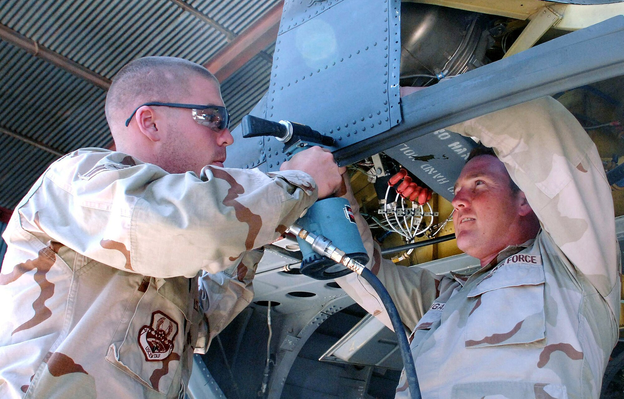 Airman 1st Class Dale Faria (left) uses a pneumatic riveter to apply rivets to the coaming of an Army CH-47 Chinook while Tech. Sgt. John Deegan holds the metal in place in April at Bagram Air Base, Afghanistan. Both Airmen have pitched in to help the Army with maintaining their helicopters. Airman Faria is a 455th Expeditionary Maintenance Squadron aircraft structural maintenance journeyman, and Sergeant Deegan is a 455th EMXS aircraft structural mainenance craftsman. (U.S. Air Force photo/Staff Sgt. Kevin Tomko)