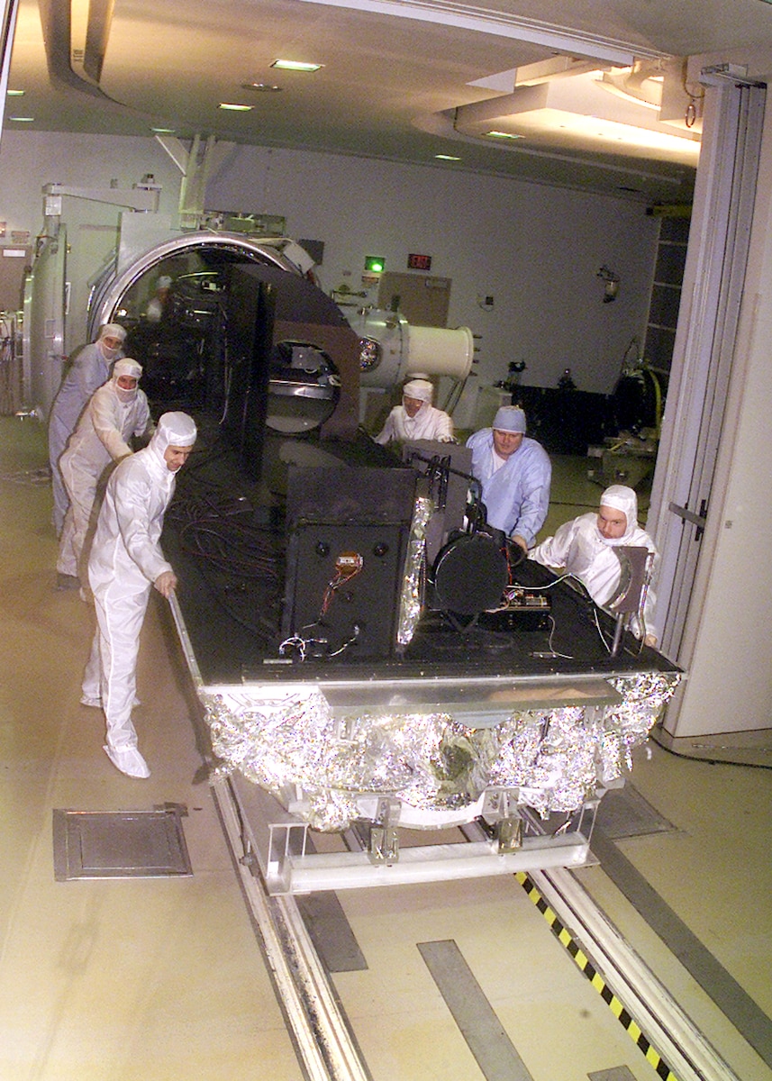 From left to right, David Stanek, instrument technician; Roger Johnson, instrument technician; Josh Drumm, systems test engineer; Ed White, senior systems test engineer; Ricky Bush, outside machinist; and Aaron Wojcik, systems test engineer, at the Arnold Engineering Development Center’s 7V Space Chamber, remove an optical bench in the clean room at the seven by 21-foot test chamber. The bench’s removal is part of a major upgrade project that began with the chamber’s demolition by Western Environmental, Inc. The changes will not significantly affect the size of the facility. Some of the improvements to the chamber will include changing the airflow from horizontal to vertical and changing the chamber to a class 1,000 (number of particles per million) clean room. 