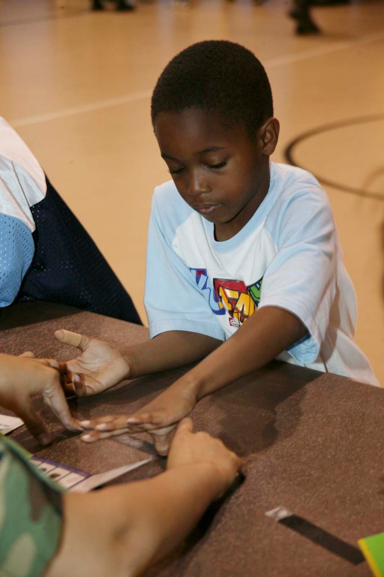 SHAW AIR FORCE BASE, S.C. -- Zhaquez, son of Dinishau and Tech. Sgt. Edward Brown, 9th Air Force Manpower analyst, dips his thumb in ink to make his fingerprint during a Cops and Kids event at the Shaw Youth Center May 14 as part of Police Week. During the week, on and off-base events included city and county police and 20th Security Forces Squadron members. Security Forces members showed children different aspects and equipment of their job at the Cops and Kids event including fingerprinting, firing positions, night vision and protective gear wear. (U.S. Air Force photo/Senior Airman Holly MacDonald)