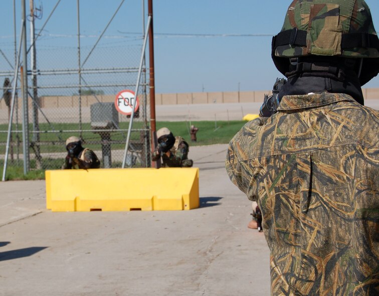 Staff Sgt. Jarrod Cappon, 319th Security Forces training instructor, aims his training weapon at the Airmen in Expeditionary Combat Skills training. The Airmen training are practicing securing an entry point. (U.S. Air Force photo/Airman 1st Class Ashley Coomes)