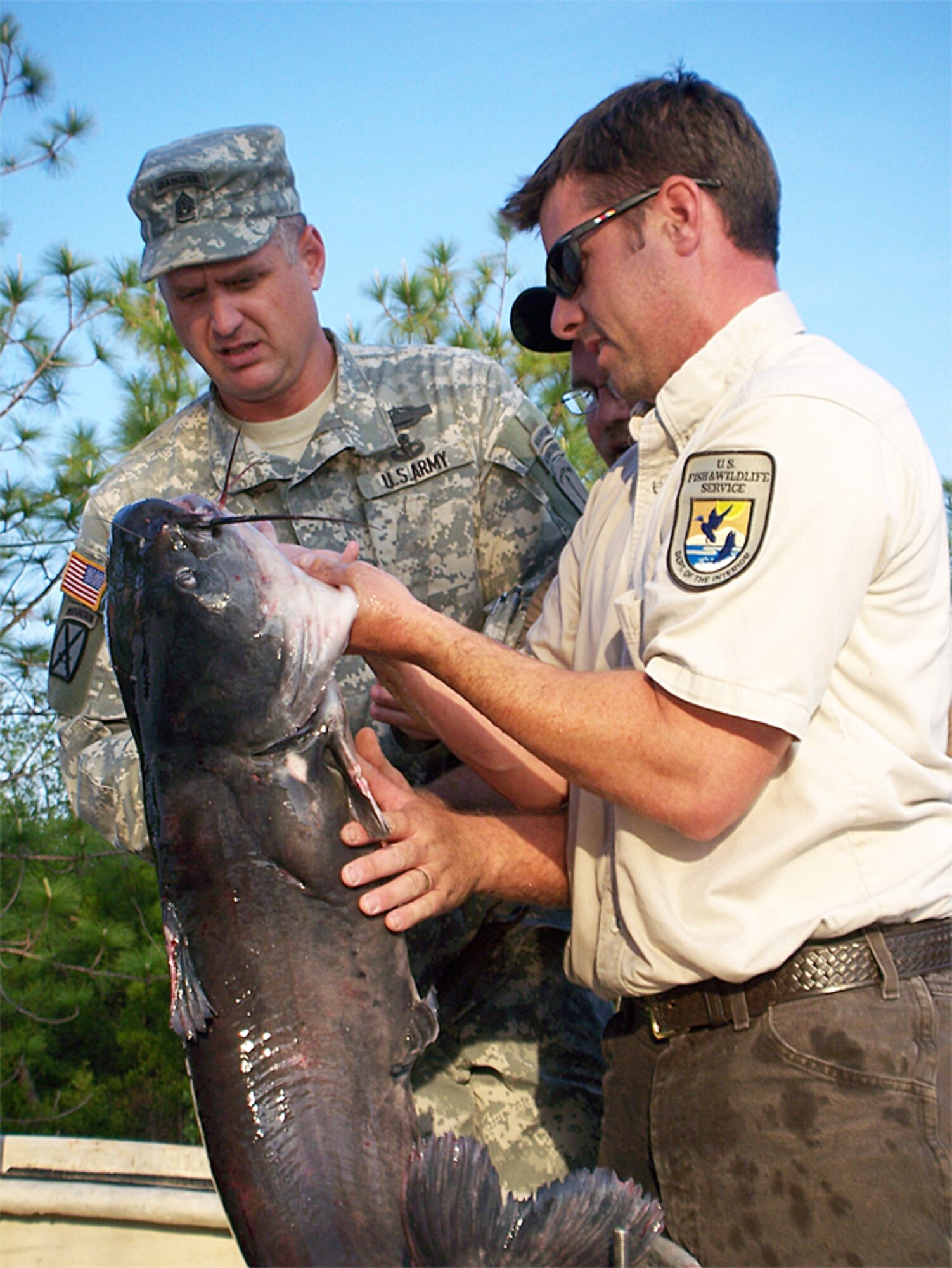 EGLIN AIR FORCE BASE, Fla. -- EGLIN AIR FORCE BASE, Fla. -- Army Command Sgt. Maj. Michael Hibbs, 6th Ranger Training Battalion, and Bill Tate, U.S. Fish & Wildlife Service aquatic biologist, release a large channel catfish into Prisoner pond in preparation for the May 26-27 Youth Fishing Rodeo. More than 3,000 catfish, even a few up to 20 pounds in weight, have been stocked in the pond to ensure all participants enjoy a high quality fishing experience.
