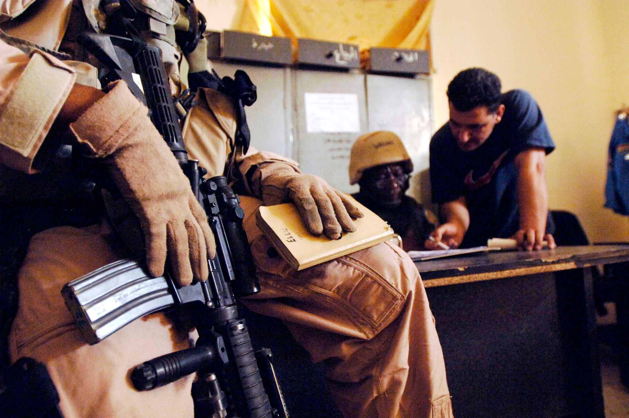 Staff Sgt. Michael Ellis waits while his co-worker discusses investigative issues with an Iraqi police official May 9 in a Baghdad police station. Members of Det. 3, 732nd Expeditionary Security Forces Squadron, perform police transition team duties of mentoring, coaching and teaching Iraqi police. (U.S. Air Force photo/Tech. Sgt. Cecilio M. Ricardo Jr.) 
