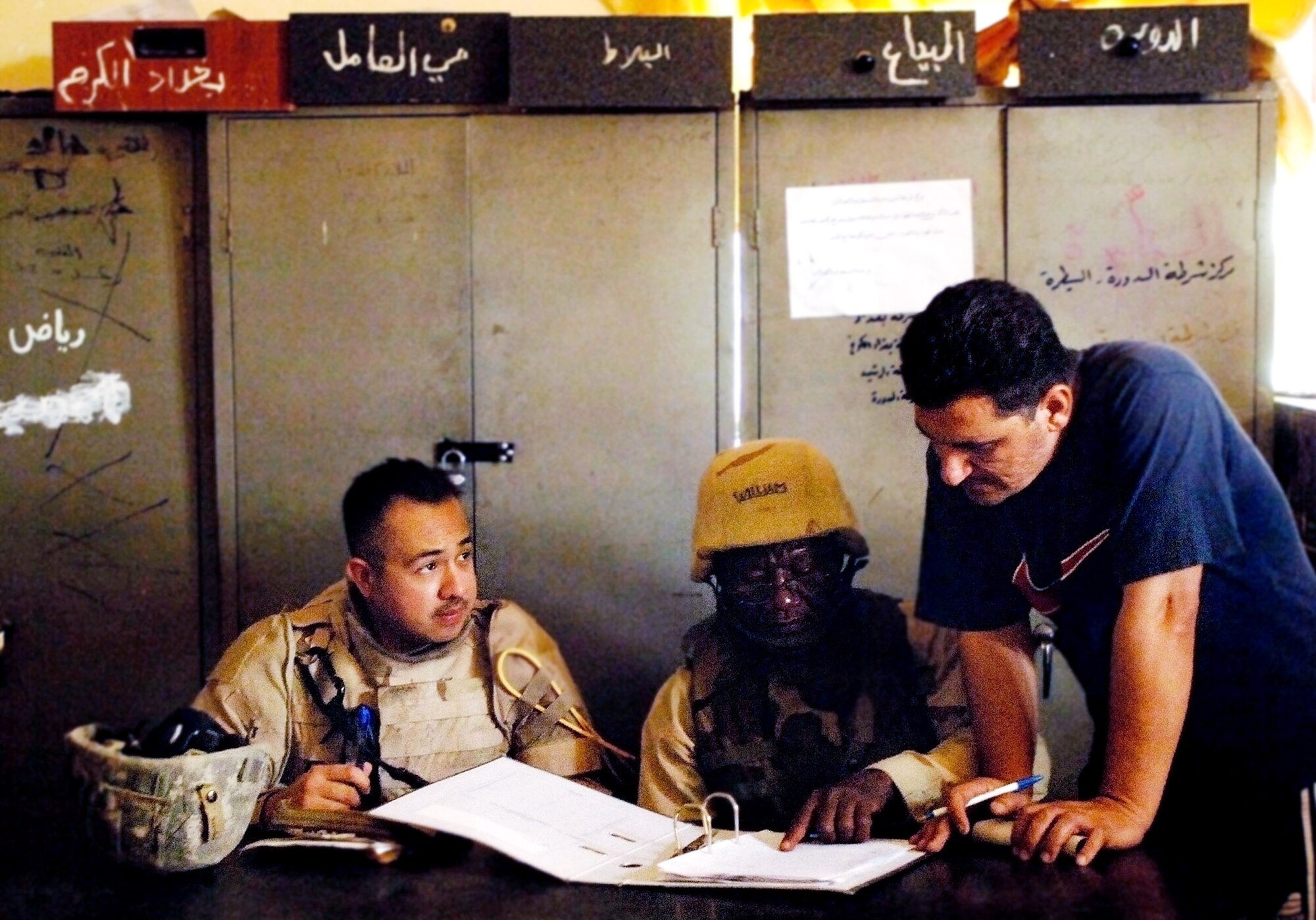 Staff Sgt. Christoper Aguirre discusses investigative reports with an Iraqi police official May 9 in a Baghdad police station. Memmbers of Det. 3, 732nd Expeditionary Security Forces Squadron, perform police transition team duties of mentoring, coaching and teaching Iraqi police. (U.S. Air Force photo/Tech. Sgt. Cecilio M. Ricardo Jr.) 
