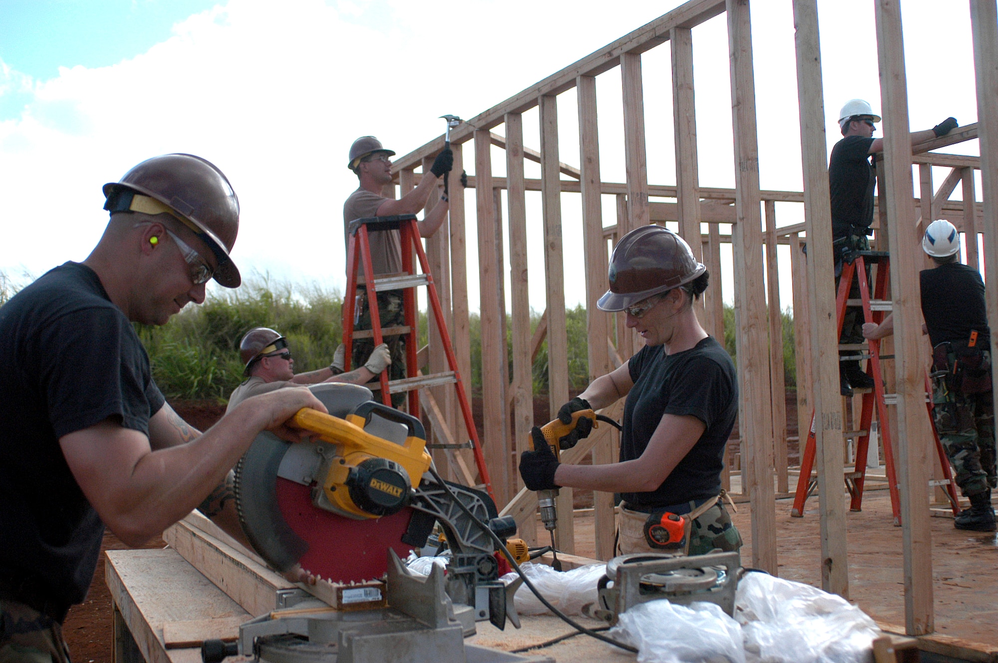 301st Civil Engineer Squadron members Staff Sgt. Jeremy Glenn (left) and Staff Sgt. Krista Kenoyer cut boards as (from left) Senior Airman Doug Weir, Senior Airman Robert Wolf, Senior Master Sgt. Skip Kiefhaber and Senior Airman Matthew Ducckett work to fram a house as parto fo a project to bui8ld housing for the elderly and handicapped next to Helemano Plantantion on Oahu, Hawaii. (U.S. Air Force Photo/Tech. Sgt. Stephen Bailey)