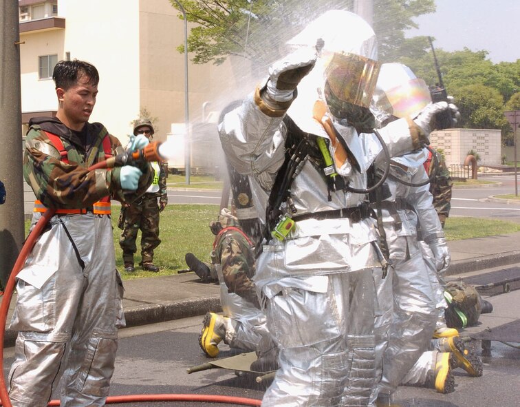 Senior Airman Jorley Vivo, 374 CES, hoses down fellow firefighters after a simulated contamination scenario during the exercise. (Photo by Airman Leandra Hernandez VIRIN 070508-F-8186H-043)
