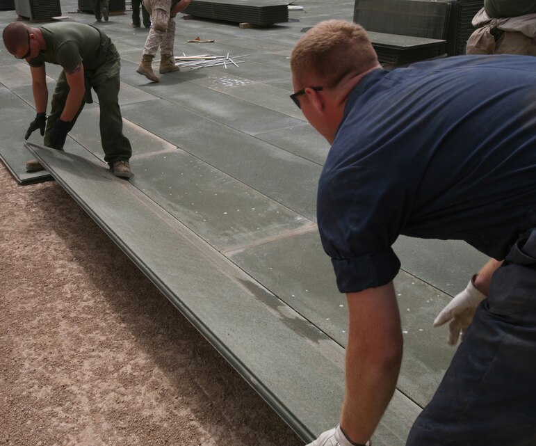 AR RAMADI, Iraq- Cpl. Robert Goodall II (left), an expeditionary airfield technician with Marine Wing Support Squadron, and Lance Cpl. Bradlee Harris, a heavy equipment mechanic with MWSS-371, lay AM-2 matting, May 18.  The Marines laid two helicopter landing pads in Ramadi.