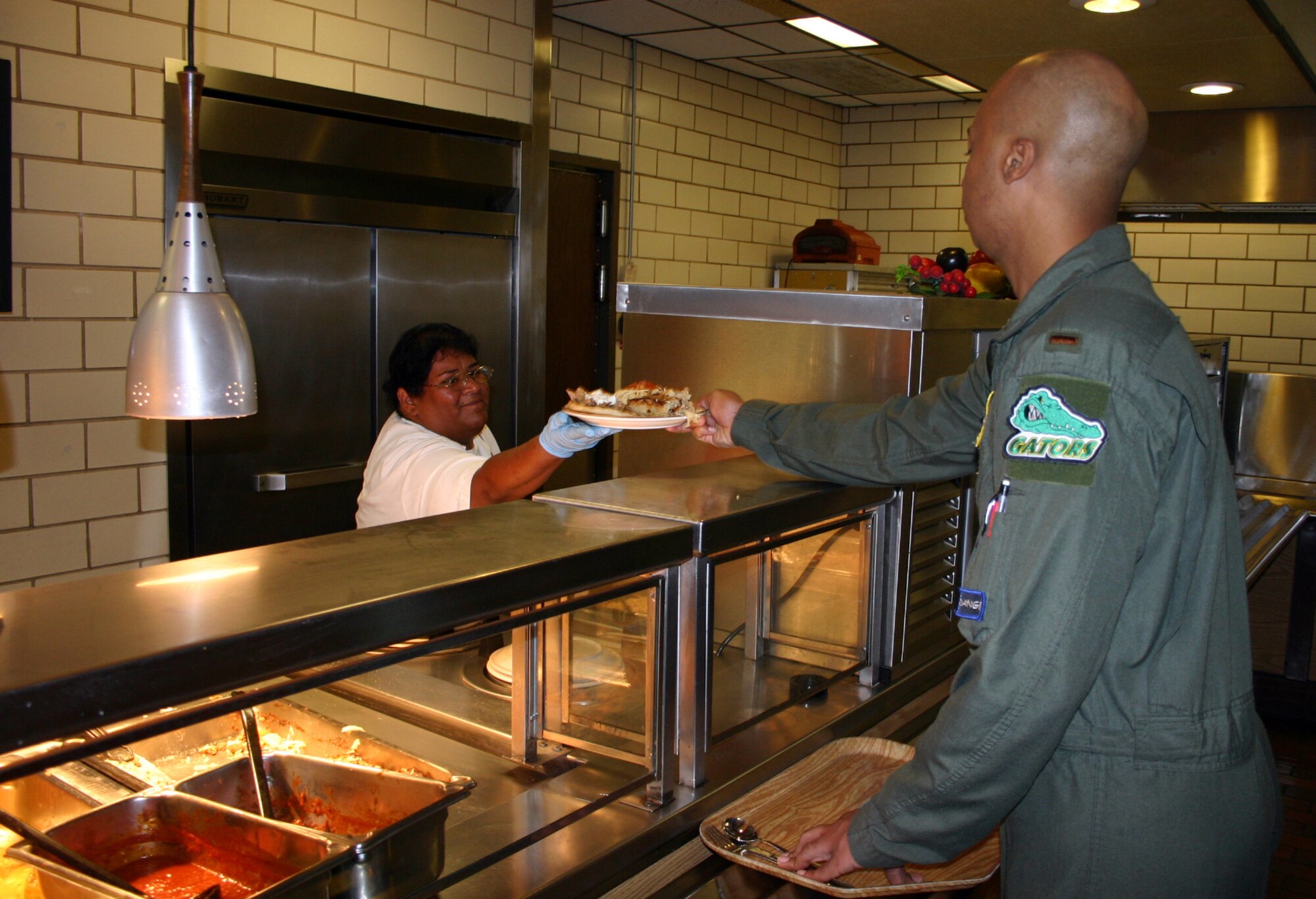 LAUGHLIN AIR FORCE BASE, Texas -- As one of the restaurant's first patrons, 2nd Lt. Khary Thompson takes a plate of food from a cook at Zorba's Greek and Italian Restaurant May 14.  The establishment opened in what used to be the Chapparal Dining Facility.  (U.S. Air Force photo by Senior Airman Olufemi Owolabi)