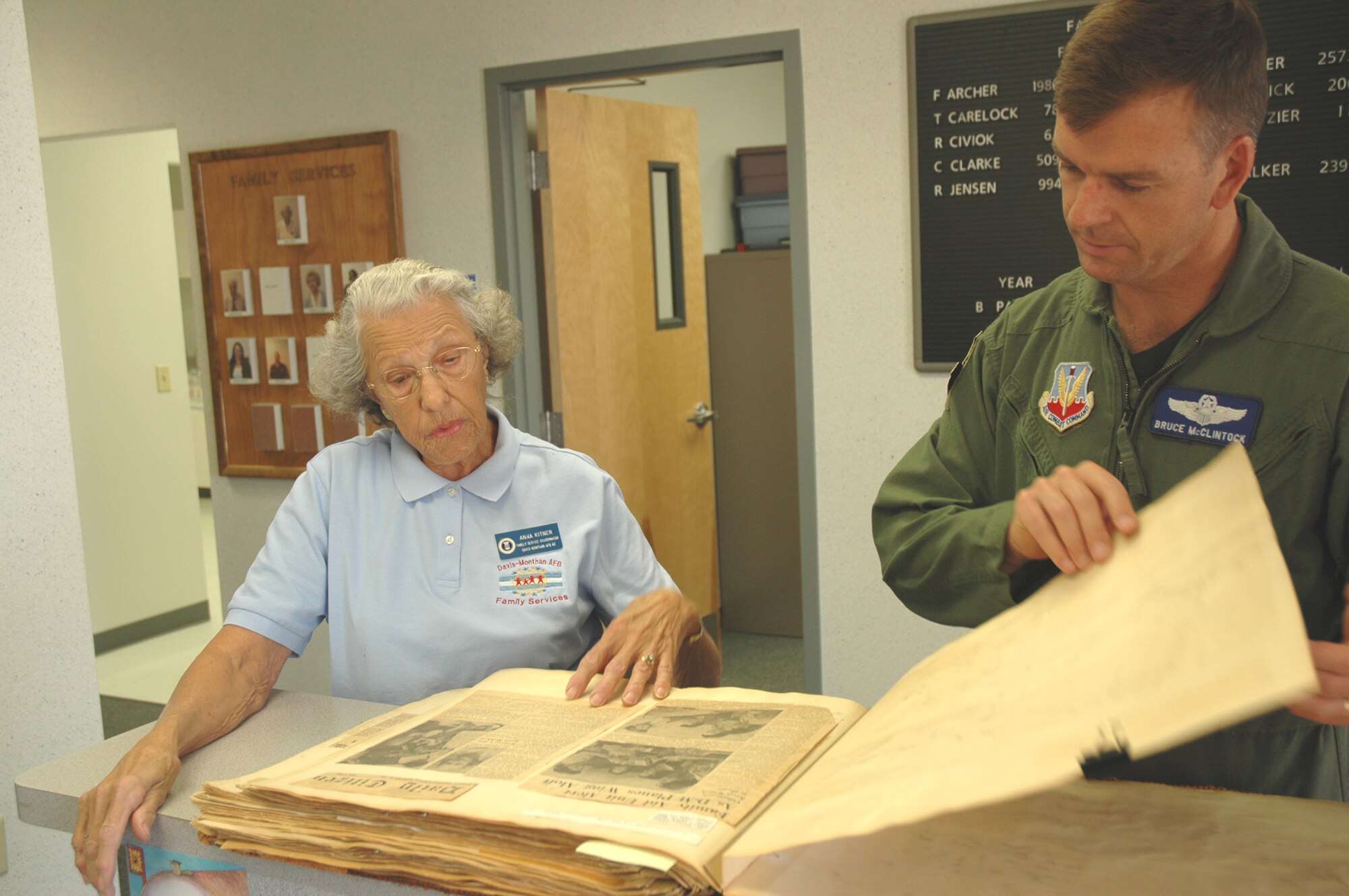Anna Kitner, a family services volunteer at the Airmen and Family Readiness Center here, shows 355th Wing Vice Commander Col. Bruce H. McClintock the first family services scrapbook created for the "Davis-Monthan Dependents Assistance" office in October 1954. (U.S. Air Force photo/Staff Sgt. Jake Richmond)