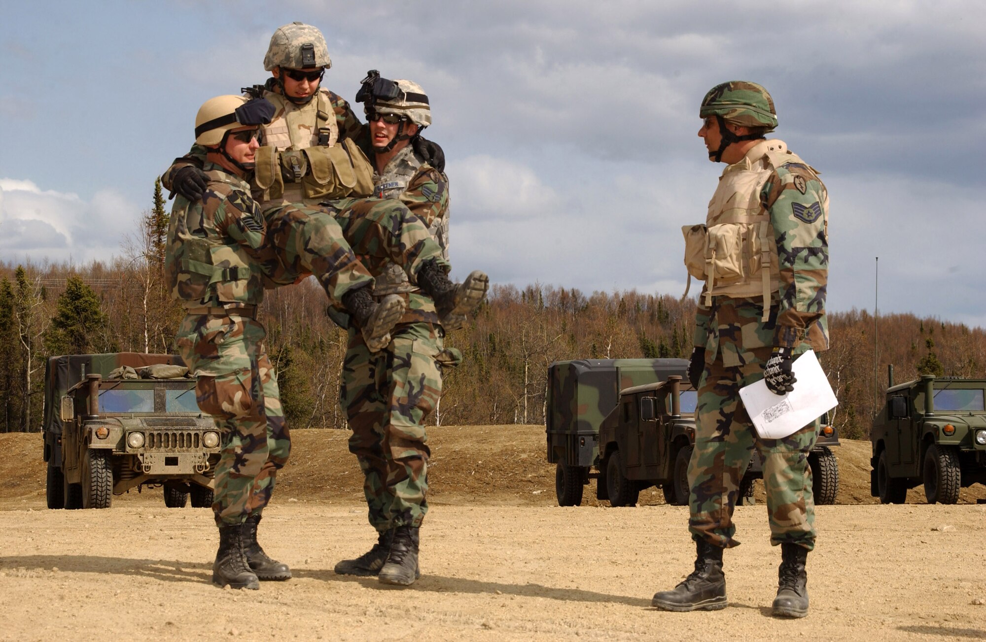 Staff Sgt. Chris Skaggs (right) observes as Tech. Sgt. Thomas Moody (left) and Senior Airman Benjamin Gartner (center) demonstrate the four-handed seat-carry to transport Airman 1st Class Steven Vonack May 15 during self-aid buddy care training.  The four 3rd Air Support Operations Squadron Airmen are participating in Operation Ursa Minor, a three-day field training exercise at Eielson Air Force Base, Alaska, designed to provide hands-on combat training and experience to Airmen before they deploy to a combat area. (U.S. Air Force photo/Airman 1st Class Jonathan Snyder)