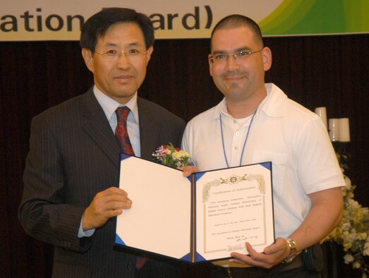 GUNSAN CITY, Republic of Korea  May 17, 2007 -- Mr. Moon, Won ik, Gunsan City Education Board President, presents a certification of authorization to Tech. Sgt. Christopher Atkinson May 16 during the 2007 English volunteer recognition dinner. Sergeant Atkinson, assigned to the 8th Fighter Wing "Wolf Pack," was one of 55 Airmen at Kunsan Air Base recognized by the local education board for their dedication in helping teach English to elementary and middle school students. (U.S. Air Force photo/Senior Airman Stephen Collier)