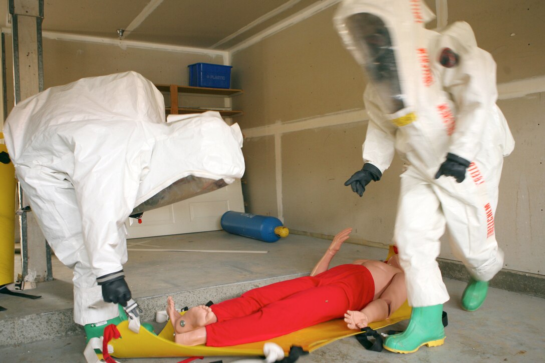 Two chemical, biological, radiological and nuclear defense Marines remove a casualty from a contaminated building during a training exercise at Stuart Mesa Housing May 17. The evolution was the final part of a seven-week course.