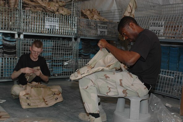 Staff Sgt. Abram Norwood (right) and Senior Airman Christopher Graham, 379th Expeditionary Logistics Readiness Squadron Expeditionary Theater Distribution Center mobility specialists, build up individual body armor vests Tuesday. (U.S. Air Force photo by Senior Airman Erik Hofmeyer)