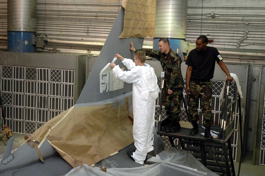 OSAN AIR BASE, Republic of Korea --  Staff Sgts. Jonathan Randolph and Dennis Eberly, and Senior Airman James Taylor, 51st Maintenance Squadron corrosion element, check the newest touches to their work on Brig. Gen. Joe Reynes' F-16 Fighting Falcon. The corrosion element was tasked with painting a Korean Conflict -era "Checkertail" design on five command jets here. (U.S. Air Force photo by Tech. Sgt. Michael O'Connor)