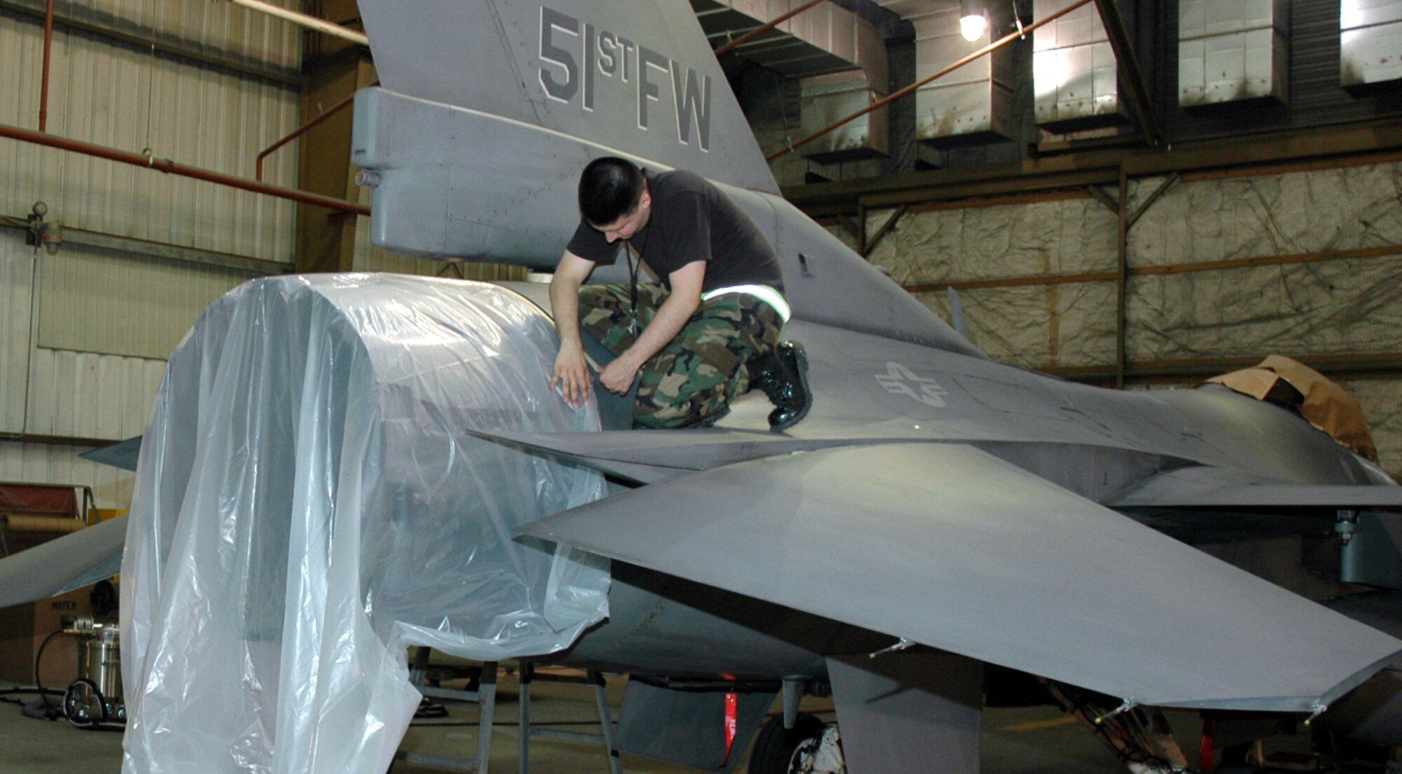 OSAN AIR BASE, Republic of Korea --  Senior Airman Dominick Fraccicia, 51st Maintenance Squadron corrosion element, prepares Brig. Gen. Joe Reynes' F-16 Fighting Falcon for its new paint job. The corrosion element is painting a Korean Conflict-era "Checkertail" design on five command jets here. (U.S. Air Force photo by Tech. Sgt. Michael O'Connor)