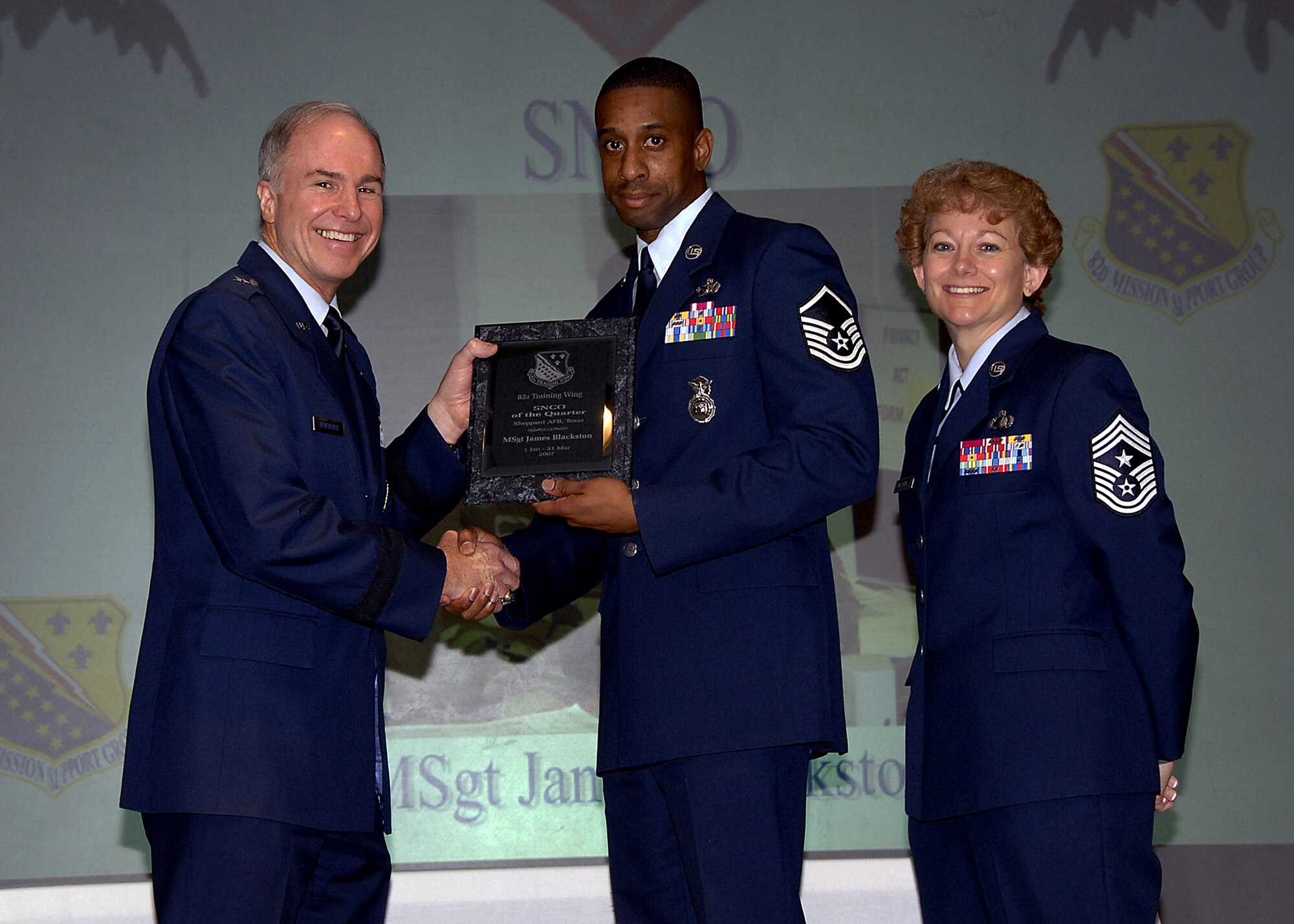The 82nd Security Forces Squadron's Master Sgt. James Blackston accepts the award of Senior NCO of the Quarter from Brig. Gen. Richard Devereaux, 82nd Training Wing commander, May 16 during the Quarterly Awards luncheon at the Sheppard Club. Sergeant Blackston was recognized for leading a 13-person team while deployed for 190 days in support of the global war on terrorism. He managed $3 million in base surveillance and targeting radars, earning recognition as the best program in the area of responsibility. Sergeant Blackston has been involved in the professional development of other Airmen by hosting a bullet writing class to more than 50 Airmen. Also pictured is Chief Master Sgt. Jeannie McLean, the 82nd TRW command chief master sergeant. (U.S. Air Force photo/Harry Tonemah)
