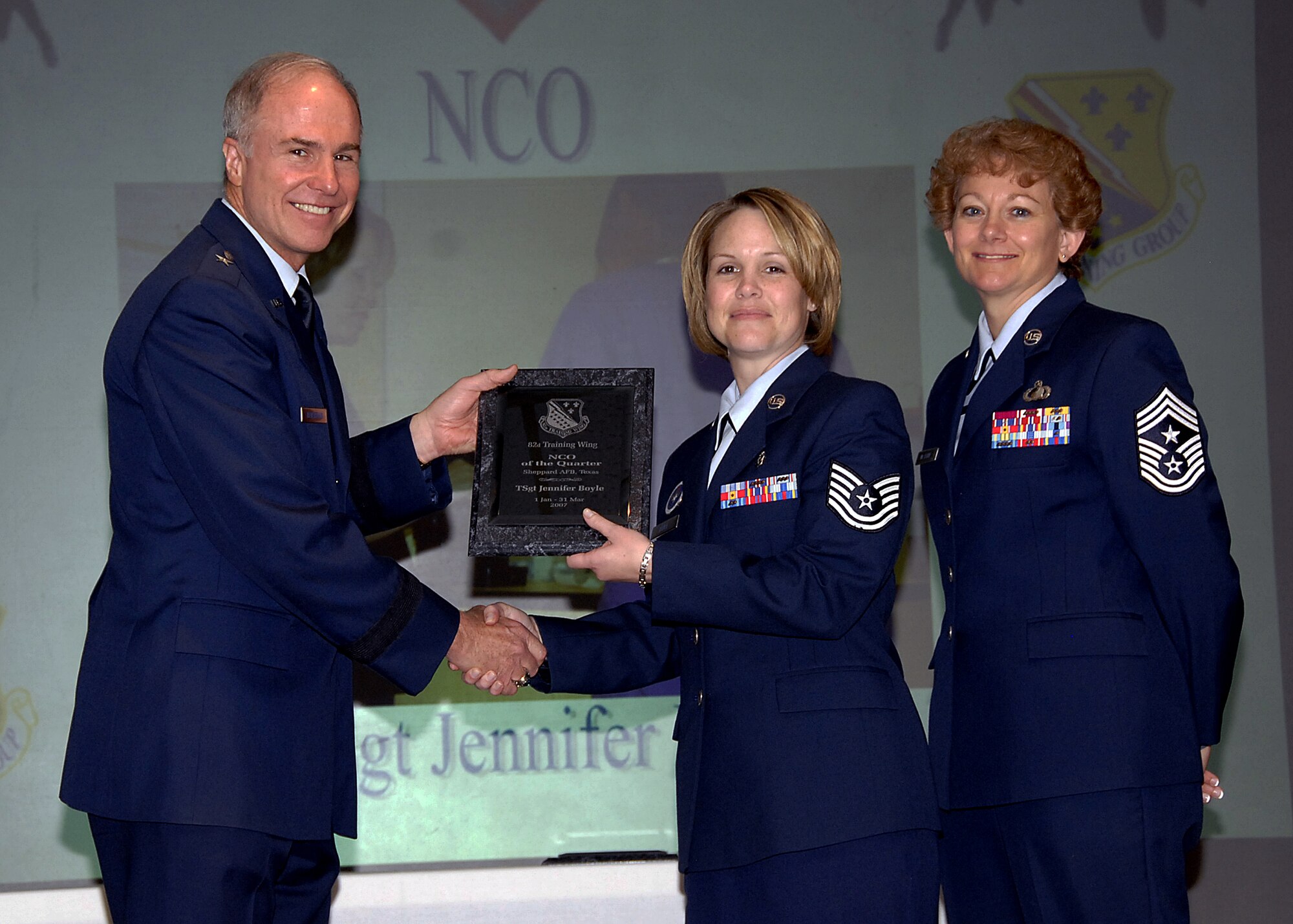 Tech. Sgt. Jennifer Boyle, center, of the 381st Training Squadron accepts her award May 16 as the NCO of the Quarter during the 82nd Training Wing Quarterly Awards luncheon at the Sheppard Club. Sergeant Boyle was recognized as a skilled instructor in the dental apprentice course, providing more than 300 instructing hours in a four-block course. She also instructed 23 individuals on basic CPR and life-saving skills. Sergeant Boyle volunteered to work as a tax advisor during the 2007 tax season, saving more than $2,000 in preparation fees for customers. Also pictured are 82nd TRW Commander Brig. Gen. Richard Devereaux and Chief Master Sgt. Jeannie McLean, the wing's command chief master sergeant. (U.S. Air Force photo/Harry Tonemah)