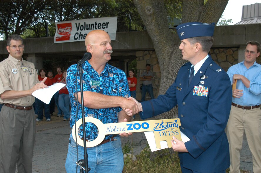 DYESS AIR FORCE BASE, Texas -- Col. Timothy Ray, 7th Bomb Wing commander, accepts the key to Zoolute from Jeff Bullock, Zoo director, who, together with Abilene leadership and community, hosted a free day at the Zoo on Armed Forces Day, May 19, to honor military servicemembers and their families. The Classical Chorus of Abilene (background) sang during opening ceremonies. Mayor Norm Archibald (not pictured) also attended the event. Tom Martin, the Zoo president (left) and a representative from Congressman Randy Neugebauer's office (right), made official declarations and presentations to Colonel Ray on behalf of the military servicemembers present. (U.S. Air Force photo/Airman 1st Class Carolyn Viss)                                 