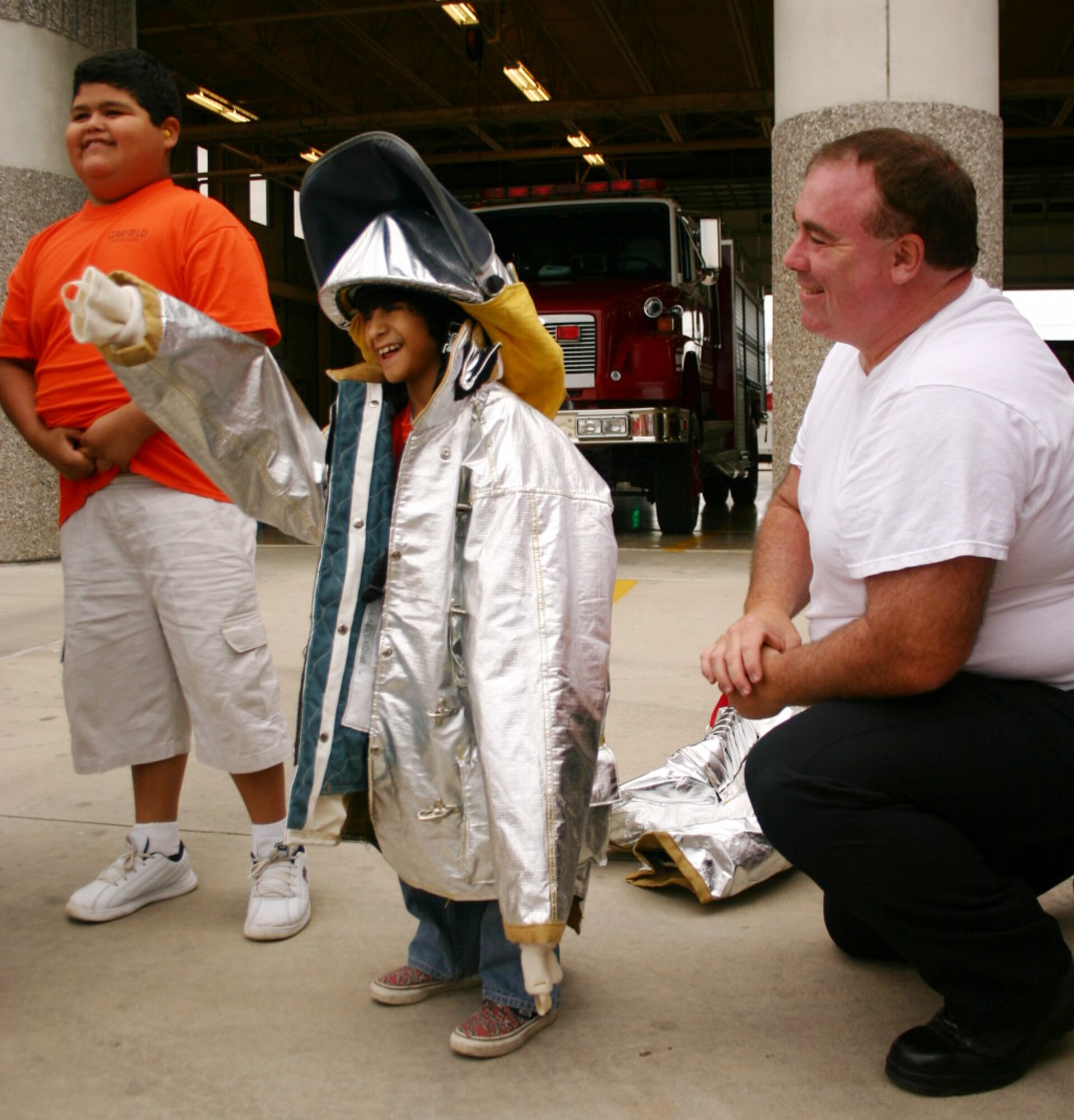 LAUGHLIN AIR FORCE BASE, Texas -- William Phaneuf, Laughlin Fire Department B-shift station captain, helps one of the smallest boys in a group of special-needs students from Del Rio experience what it's like to wear the gear the firefighters of the 47th Flying Training Wing wear for safety while fighting fires. (U.S. Air Force photo by Airman Sara Csurilla)