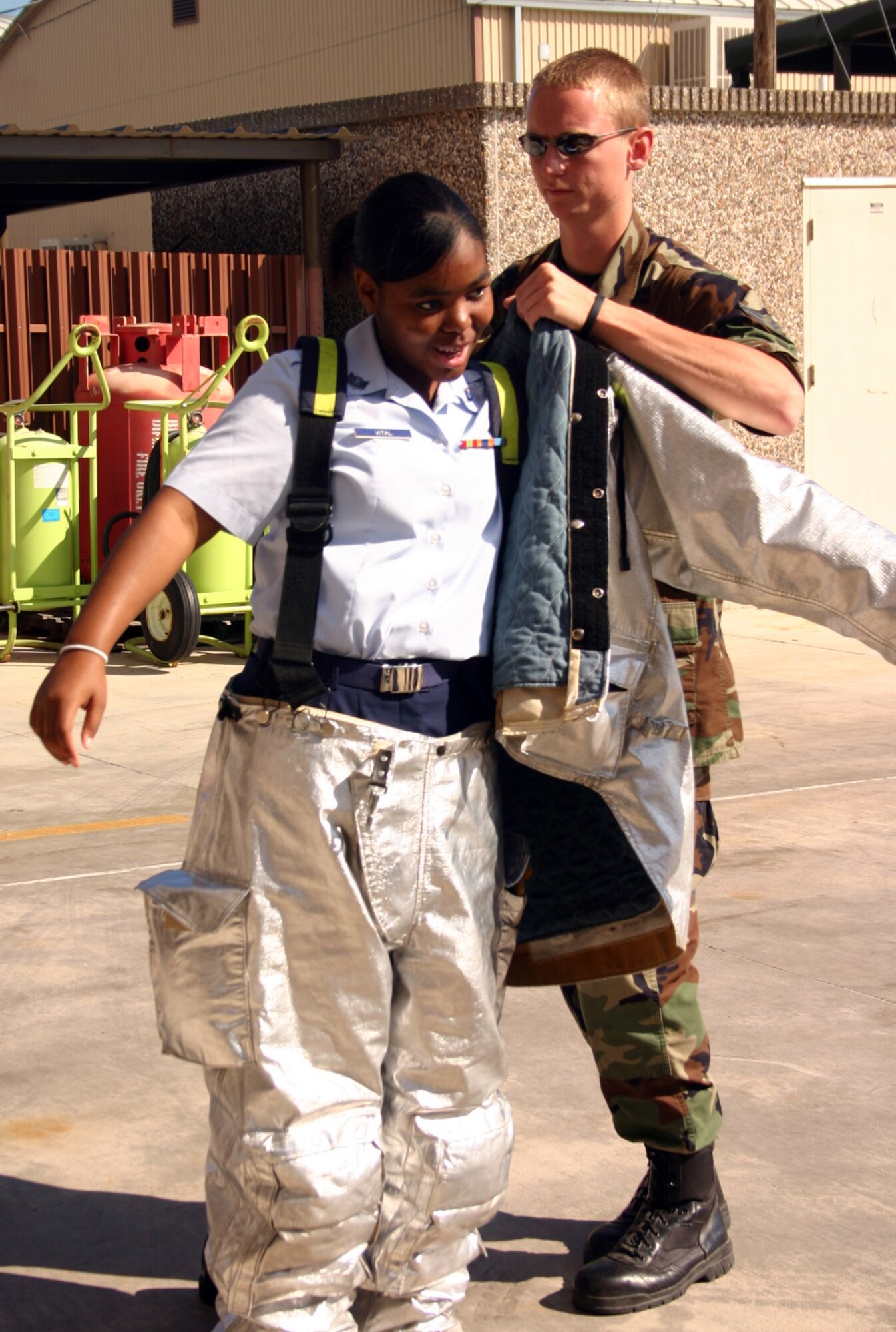 LAUGHLIN AIR FORCE BASE, Texas -- Airman 1st Class Steven Featherston, 47th Flying Training Wing, helps a young lady from a Junior Reserve Officer Training group get a better idea of what it would be like to be a military firefighter by assisting her with the safety gear they have to wear when they prepare to encounter a fire.  (U.S. Air Force photo by Airman Sara Csurilla)