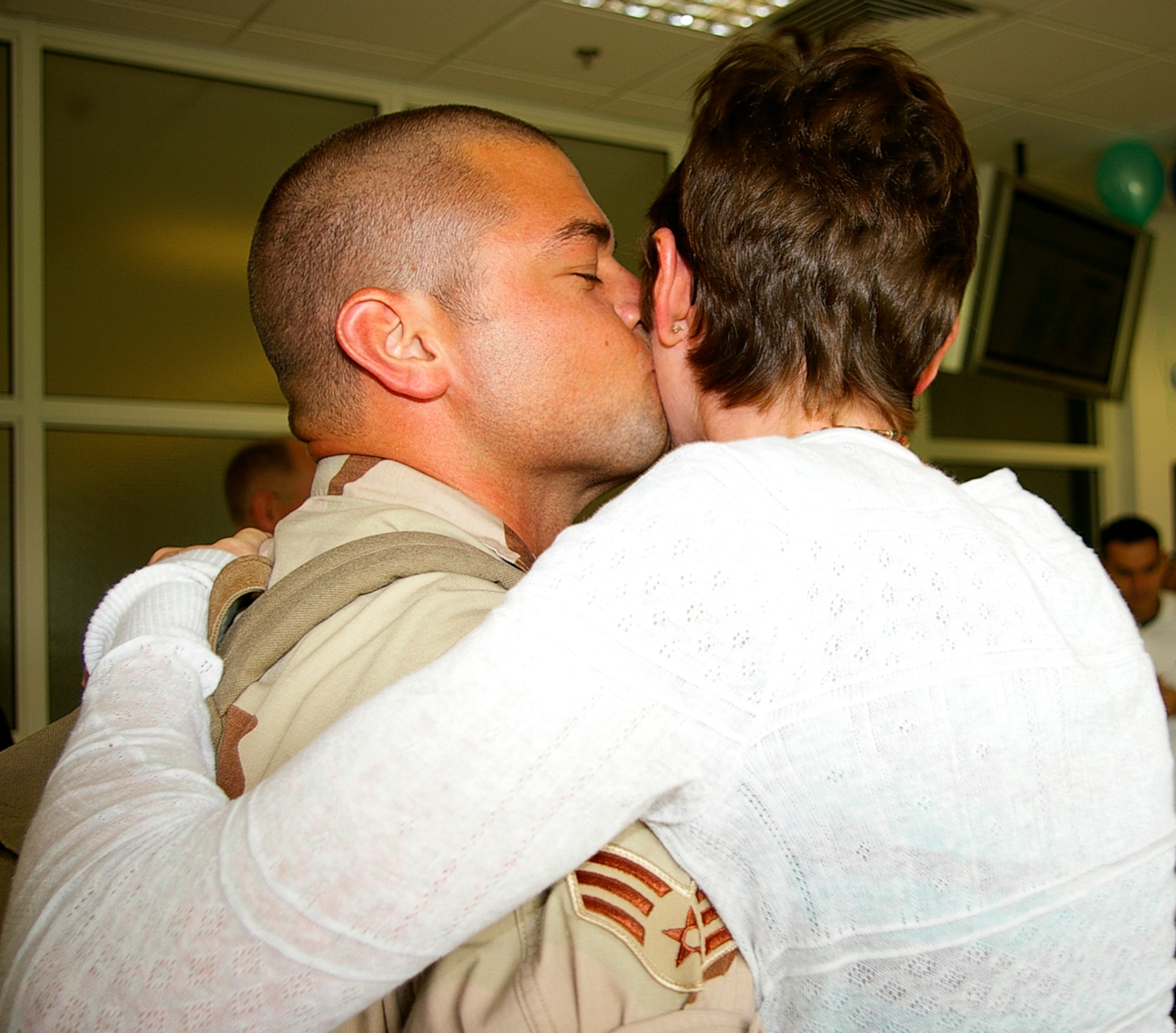 Airman 1st Class Chad Hayes, 100th Communications Squadron, kisses his wife, Crystal, as he returns to RAF Mildenhall May 19 after a deployment to southwest Asia. (U.S. Air Force photo by Karen Abeyasekere)