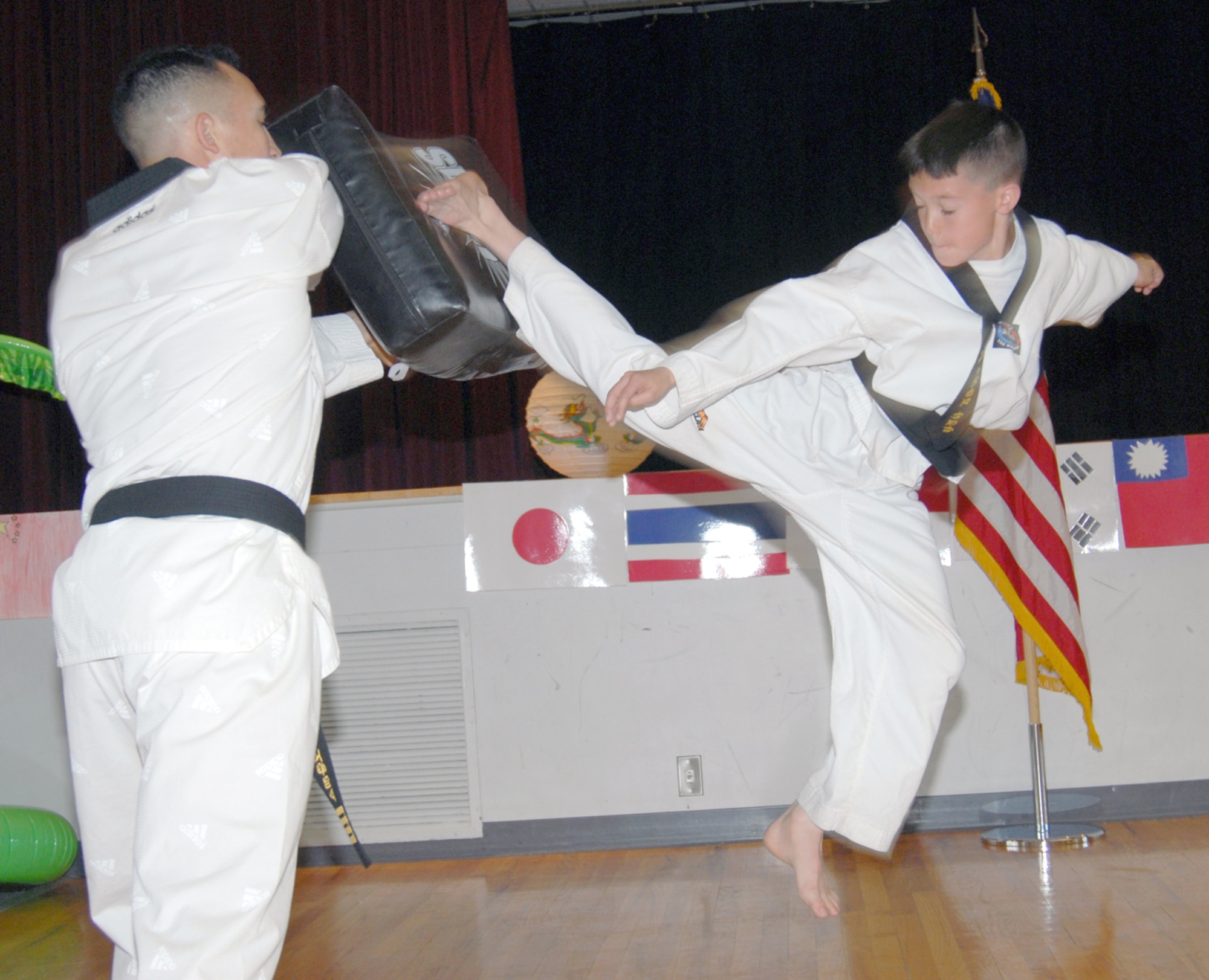 Dakota Morales kicks a pad held by his father, 1st Lt. Nicki Morales, 90th Logistics Readiness Squadron, during their tae kwon do demonstration at the Asian-Pacific American food sampling in the Pronghorn Center May 11. Dakota, 11, is a second degree black belt with eight years of experience. Lieutenant Morales has practiced tae kwon do for 22 years and is a fourth degree black belt (Photo by Bernie Ernst).