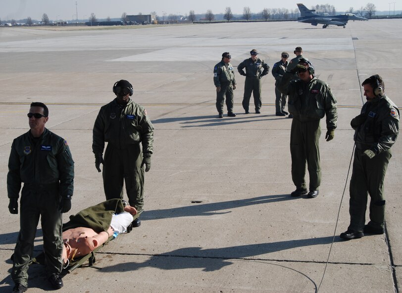 An F-16 sits in the background as team members from the 932nd Aeromedical Evacuation Squadron get a litter ready to load on a C-130 from the 908th Airlift Wing out of Maxell AFB.  Photo/ Capt. Stan Paregien