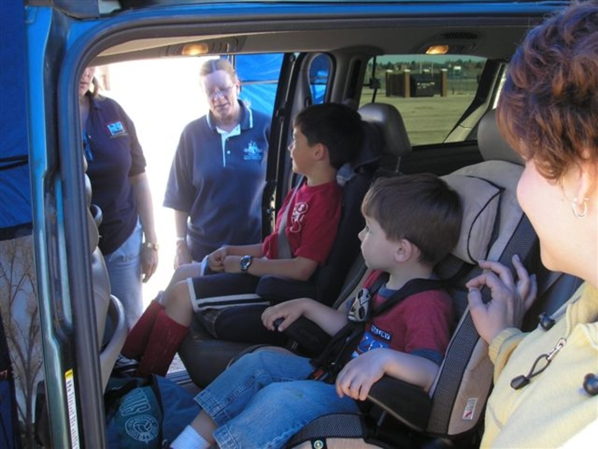 Anna Thompson, Wyo. Child Passenger Safety Instructor, and Bridget White, car seat inspector, inspects a vehicle to ensure the children, Joshua and Matthew Palazzo, are securely fastened and the seats are properly installed during a family child care open house April 28. The children's mother, Kathy Palazzo, looks on (Courtesy photo).