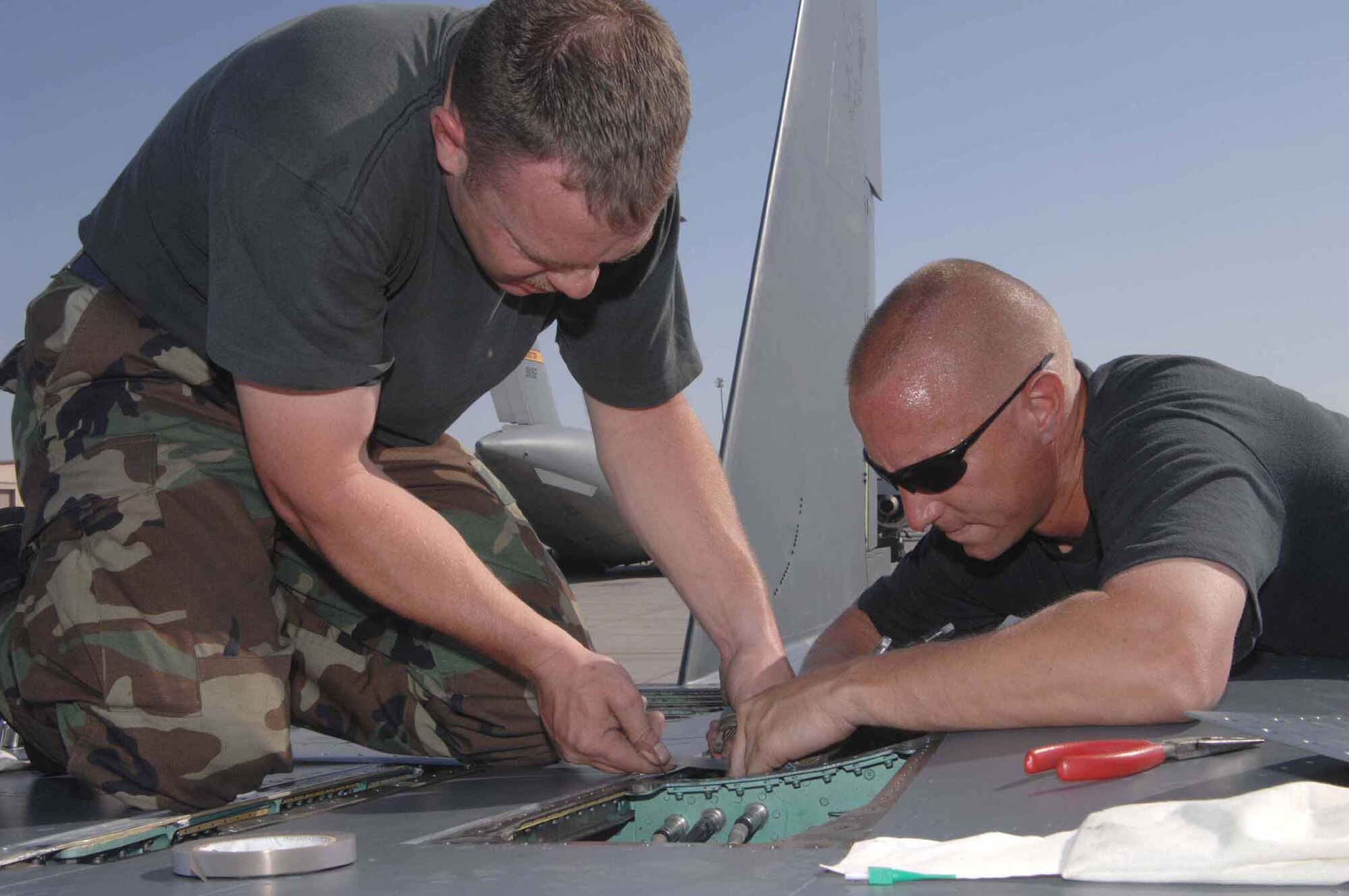 NELLIS AIR FORCE BASE, Nev. -- F-15E avionics technician Tech. Sgt. Eric Burke and avionics electrician Tech. Sgt. Christopher Alvarado, both with the 389th Aircraft Maintenance Unit, rerun control wires on top of an F-15E Strike Eagle during maintenance operations May 18 at Nellis Air Force Base. Aircrews and maintenance troops from the 389th and 391st Fighter Squadrons and 389th and 391st AMUs at Mountain Home Air Force Base traveled to Nellis earlier this month to complete a week-long weapons instructor course. The temporary duty assignment became the first for the 389th FS since becoming an F-15E Strike Eagle squadron in March. (U.S Air Force photo/Senior Airman Larry E. Reid Jr.)