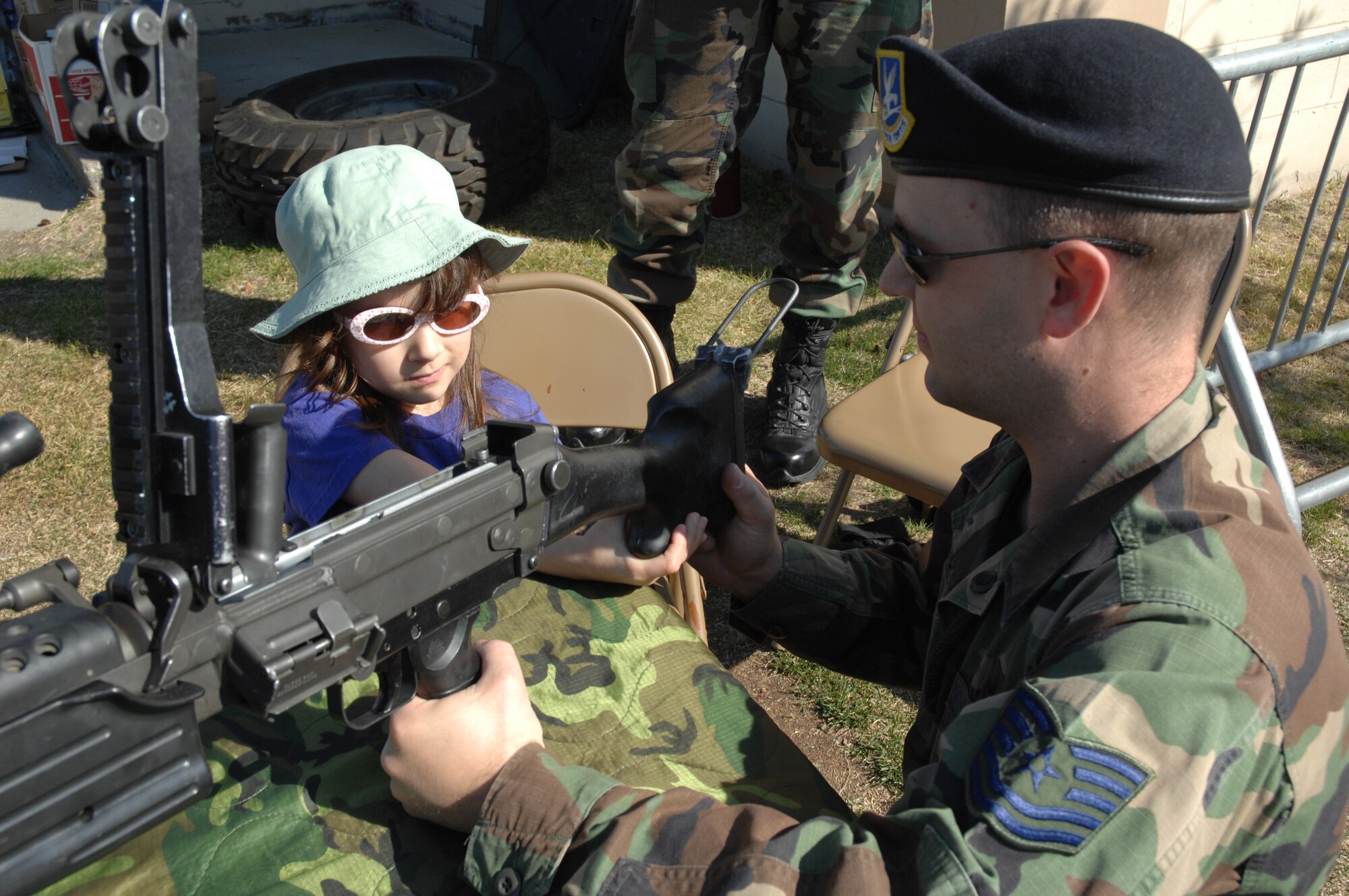 EIELSON AIR FORCE BASE, Alaska -- Tech. Sgt. Sheldon Rees, 354th Security Forces Squadron Assistant NCOIC combat arms training and maintenance, explains the functions' of an M-249 automatic rifle to Morgan Ossman, daughter of Capt. Derrick Ossman during Police Week May 19, here at Eielson AFB, AK. Police Week is an annual event hosted by the 354th SFS in honor of National Police Week, among many of the activities occurring during the week is a weapons display to promote weapons safety to the general public.  (U.S. Air Force photo by Staff Sgt. Tia Schroeder)
