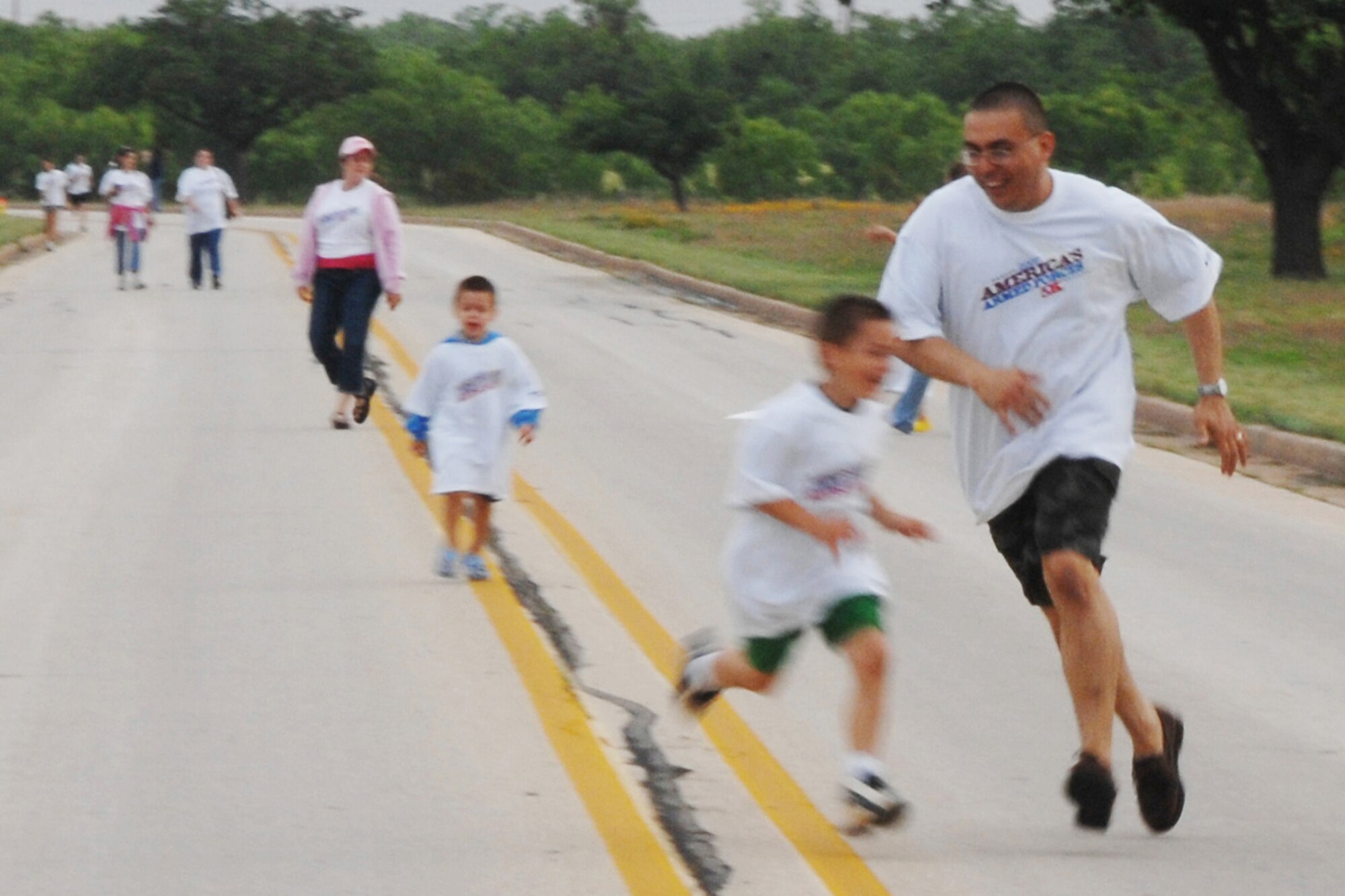 DYESS AIR FORCE BASE, Texas - Lt. Col. Andreas Walsh (right) with wife, Mia (background), and sons (right to left) Carter (6) and Cameron (4), make their way to the finish line during the America's Armed Forces Kids Run at Dyess May 19. Their youngest son, Carson (2, not visible), ran behind his father. The 5k event is held on military installations world wide in celebration of Armed Forces Day. (U.S. Air Force photo/Airman 1st Class Jennifer Romig)