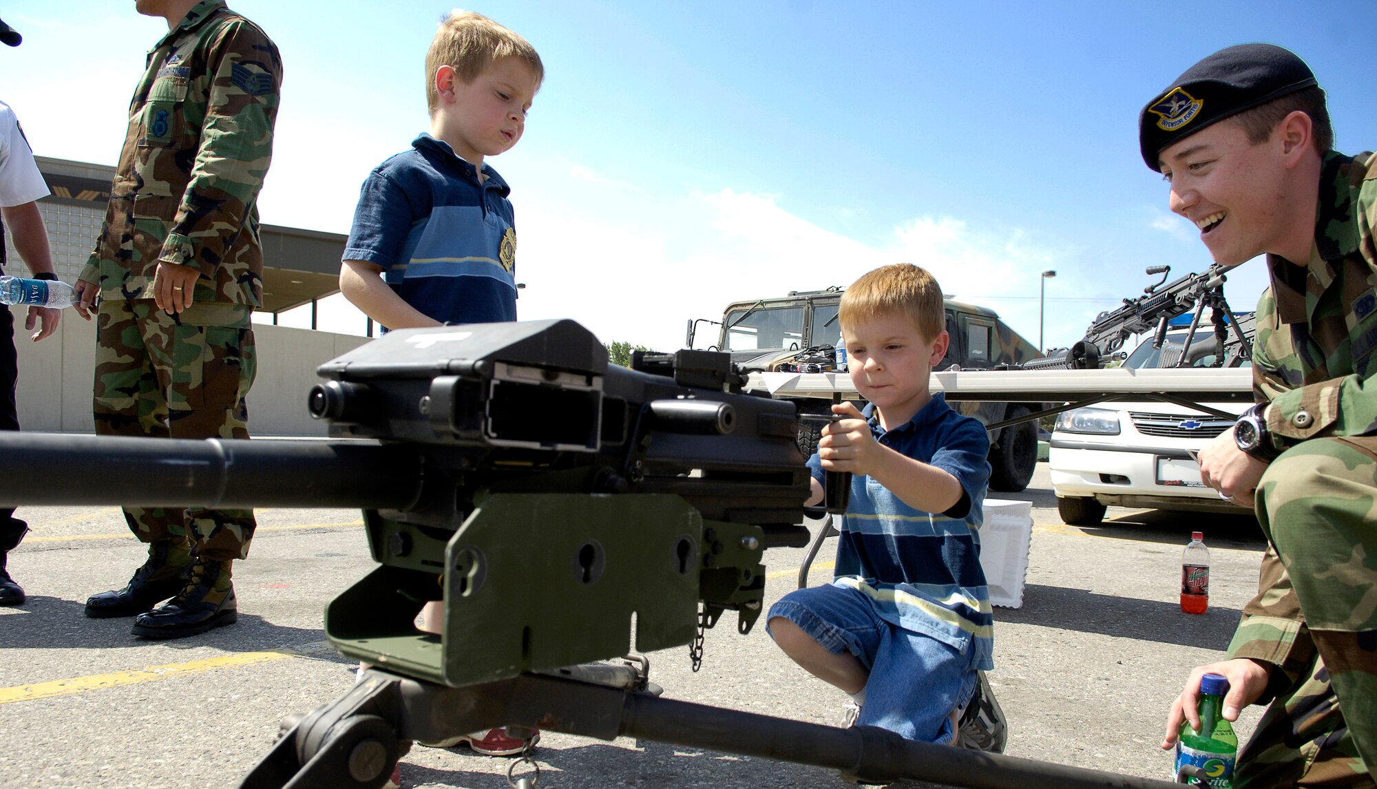 MOUNTAIN HOME AIR FORCE BASE, Idaho -- Senior Airman Thomas Price, 366th Security Forces Squadron, shows Sydney and Avery Phillips the correct way to handle a Mark-19 grenade launcher during a security forces weapons display May 17 in the Base Exchange parking lot. The hands-on exhibit was one in a series of events hosted by the 366th SFS during the base's National Police Week observance. (U.S. Air Force photo/Airman First Class Ryan Crane)