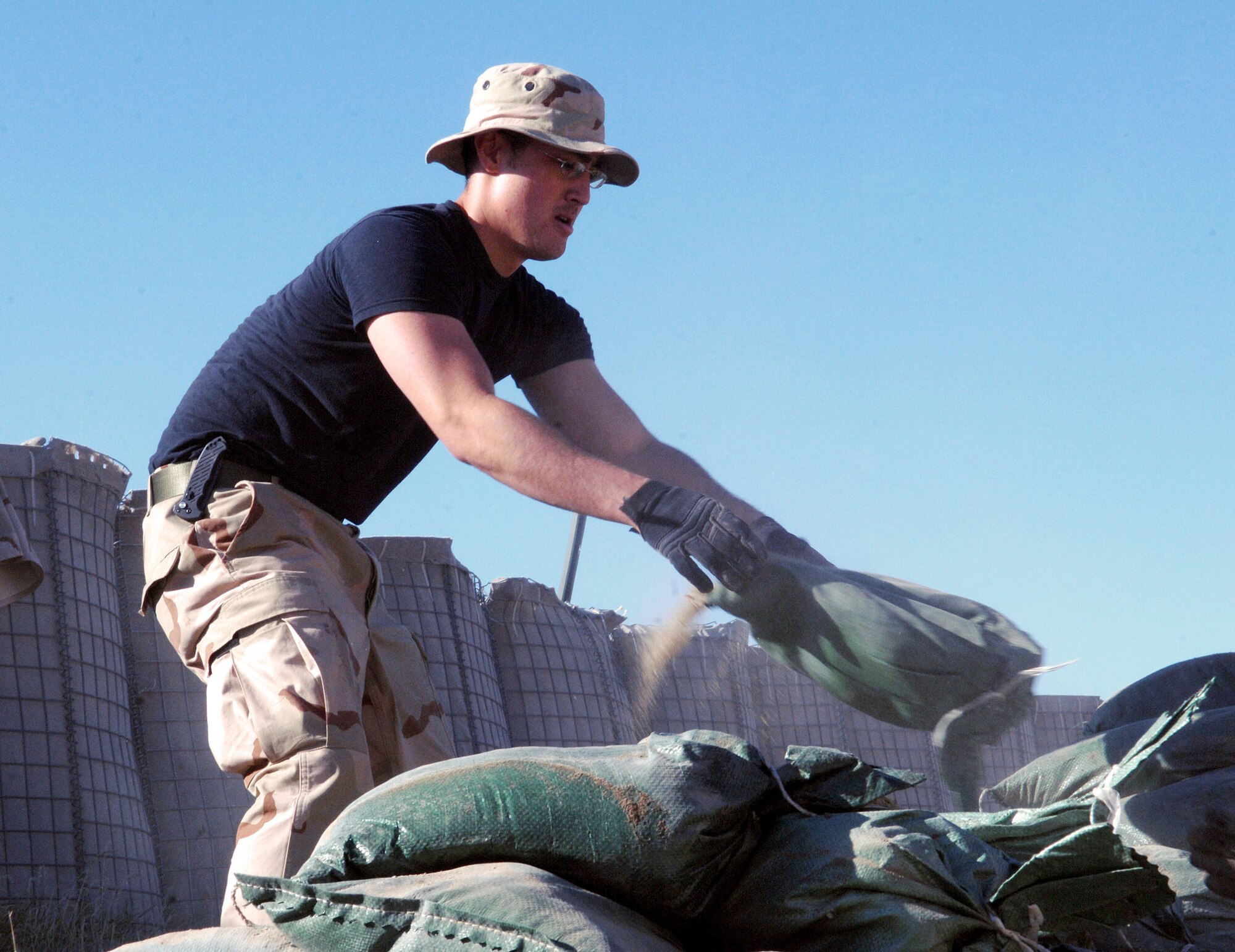 Senior Airman Bradley Luu removes sandbags in preparation for an upgrade to the deployed Airmen's living quarters on Camp Cunningham May 22 at Bagram Airfield, Afghanistan. The existing B-Huts the Airmen live in will be relocated to this area to make way for sturdier relocatable buildings. Airman Luu is assigned to the 455th Expeditionary Communications Squadron and deployed from Cannon Air Force Base, N.M. (U.S. Air Force photo/Staff Sgt. Craig Seals)
