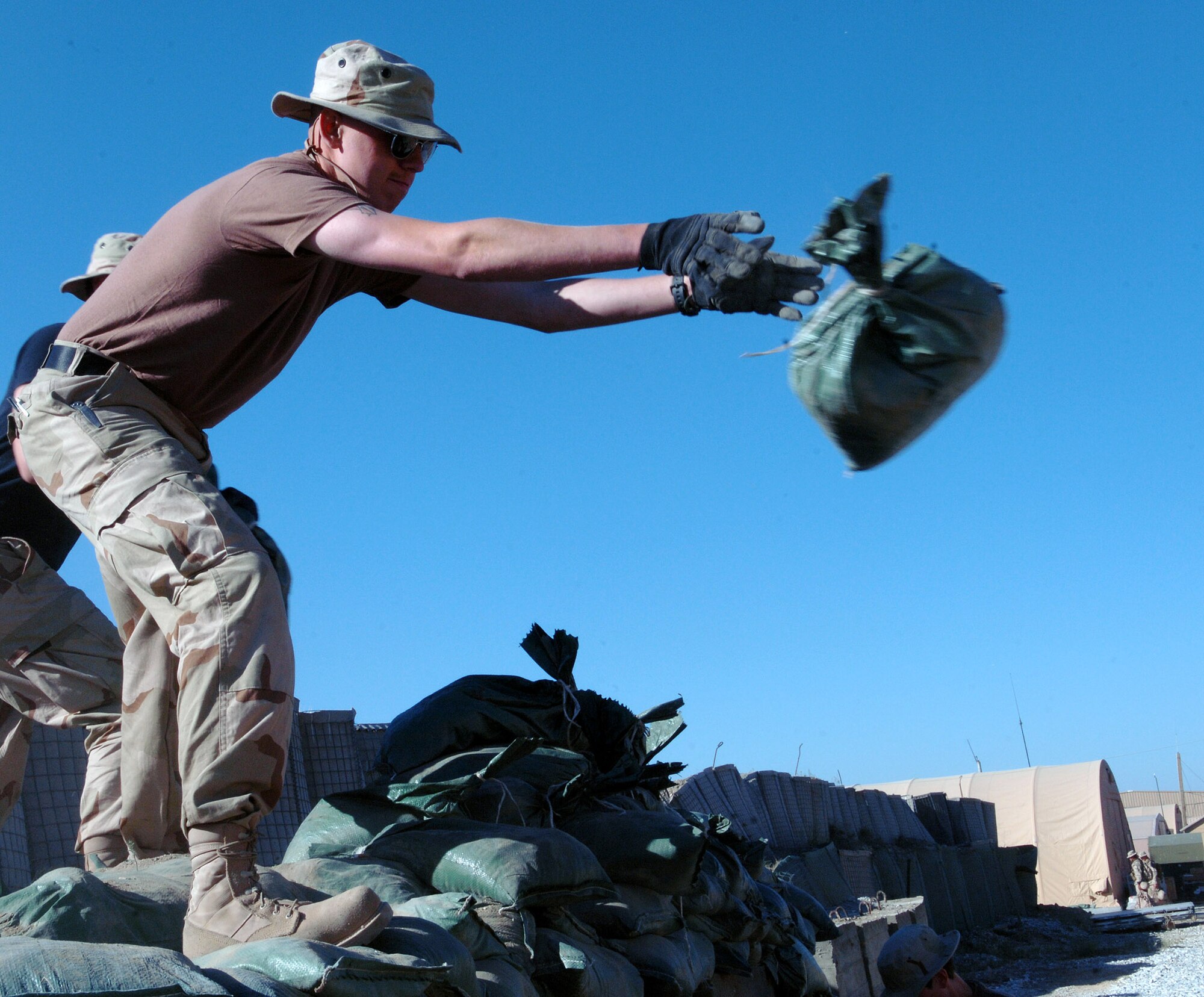 Airmen from the 455th Air Expeditionary Wing remove sandbags in preparation for an upgrade to the deployed Airmen's living quarters on Camp Cunningham at Bagram Airfield, Afghanistan May 22. The existing B-Huts the Airmen currently reside in will be relocated to this area to make way for sturdier relocatable buildings. The upgrade is currently scheduled to begin with eighteen B-Huts. (photo by Staff Sgt. Craig Seals)