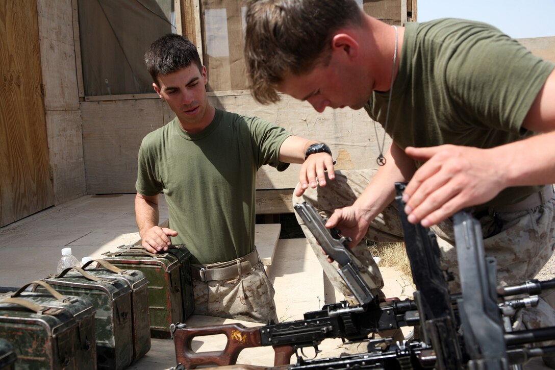 Lance Cpl. Jerimy J. Goulart, left, inspects the readiness of a section of machine guns at Camp Baharia, Iraq, May 23 prior to being issued to a graduating class of Iraq's Provincial Security Forces. Goulart, a rifleman with L Company, 3rd Battalion, 6th Marine Regiment, Regimental Combat Team 6, along with a handful of other 3/6 Marines, was dispatched here to serve as a Marine liaison for the class. Goulart was the troop handler for fourth squad, and had oversight of 12 PSF recruits.