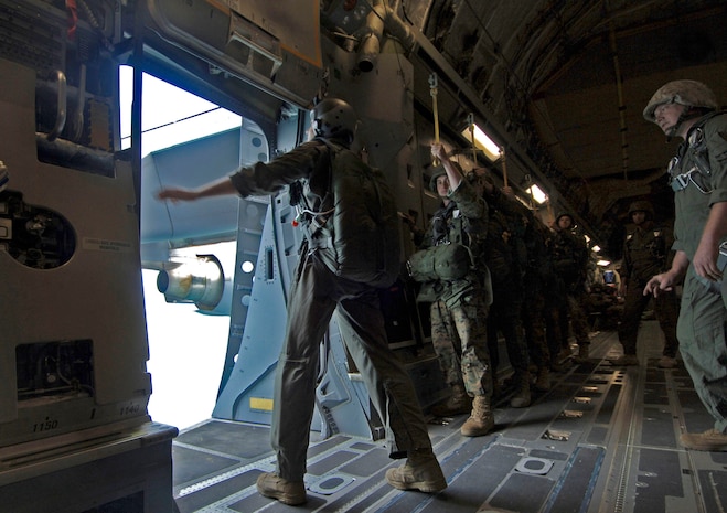 Marines stand by as Marine Sgt. Brian Trafton, 2nd Air Delivery jump master, checks and secures the rear door opening where the Marines will be jumping 2,000 feet to their target area May 18.  (U.S. Air Force photo/Staff Sgt. April Quintanilla)