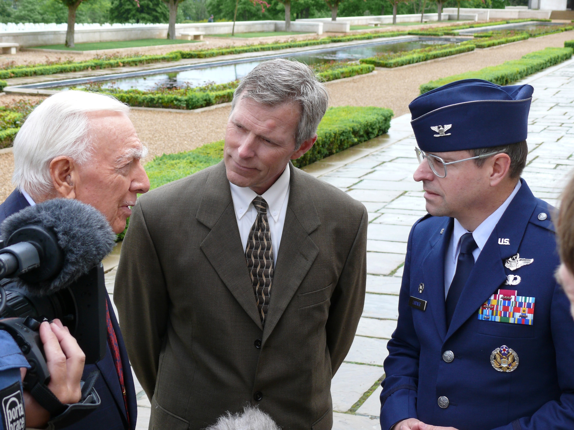 Journalist Walter Cronkite (left) tells Col. Blake Lindner and David Bedford a story about the war for a special being taped for PBS May 23 at the Cambridge American Cemetery. The three stand beside the "Wall of the Missing" identifying 5,126 names of those who were not recovered during World War II. Colonel Lindner is the commander of the 501st Combat Support Wing and Mr. Bedford is the Cambridge American Cemetery superintendent. (U.S. Air Force photo/Tech. Sgt. Scott Wakefield) 