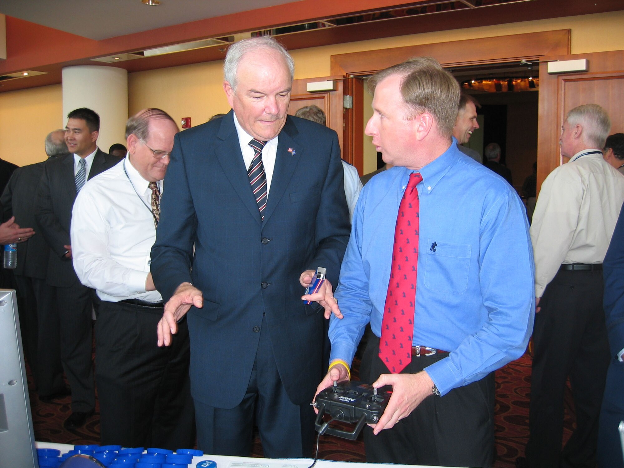 OFFUTT AIR FORCE BASE, Neb. -- Secretary of the Air Force Michael W. Wynne (left) talks with Brian Mitchell while visiting the Air Force Research Laboratory Munitions Directorate technology display booth today at the Intelligence Surveillance Reconnaissance Symposium being held at Offutt AFB, NE. Mitchell, a marketing support contractor at Eglin Air Force Base, is demonstrating the use of a remote control (U.S. Air Force photo by Mike Wallace).
