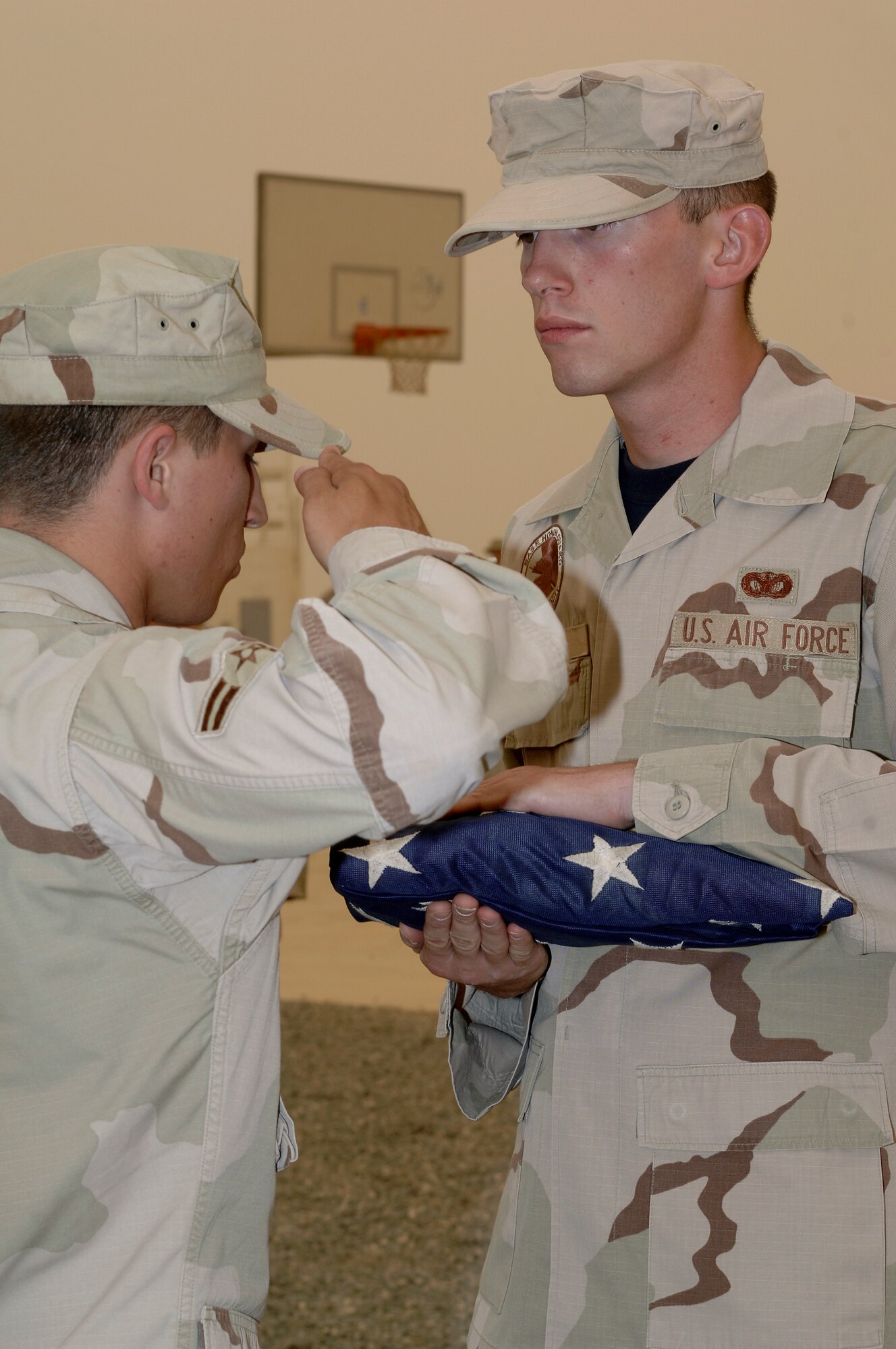 Senior Airman Mark King, of the 386th Expeditionary Security Forces Squadron, holds the flag, while Airman 1st Class James Fowler, also of the 386th ESFS, renders a salute, during a memorial retreat May 18, 2007. Security forces Airmen performed the ceremony in honor of National Police Week. The 386th ESFS also paid a special tribute to Staff Sgt. John Self, a security forces dog handler killed in action May 14. (U.S. Air Force photo by Staff Sgt. Raymond Mills)
