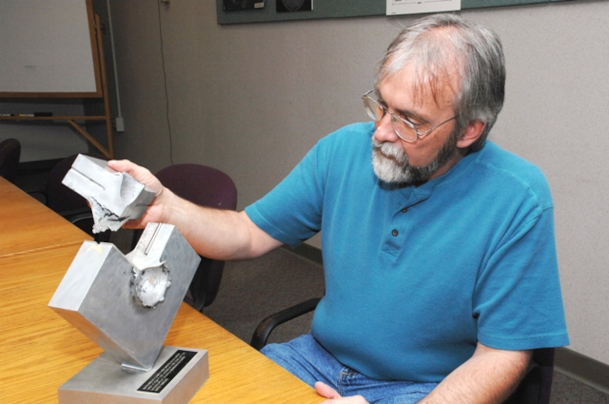 Brian Roebuck, an Aerospace Testing Alliance test engineer for AEDC’s Hypervelocity Impact Range, holds a section of an aluminum target plate – showing an impact crater created by a hypervelocity projectile that struck the plate during a test. ATA is the support contractor for the base. (Photo by David Housch) 