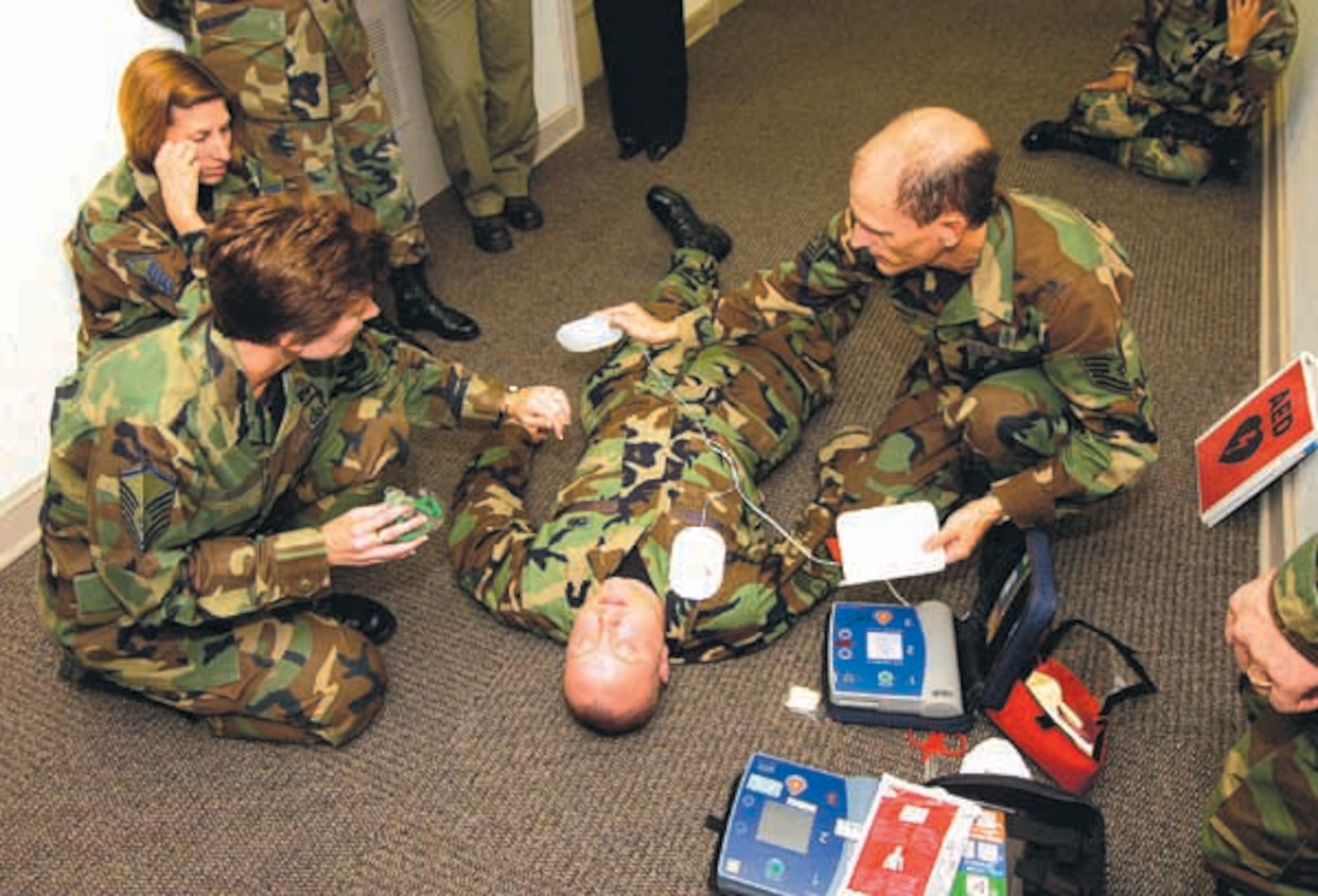 With Staff Sgt. Isaac Wilson acting as a heart attack victim in Bldg. 460, Tech Sgt. Mickey Leckie, right, and Master Sgt. Beverly Justice go through rescue procedures using the Automatic External Defibrillator during a recent training session. 
