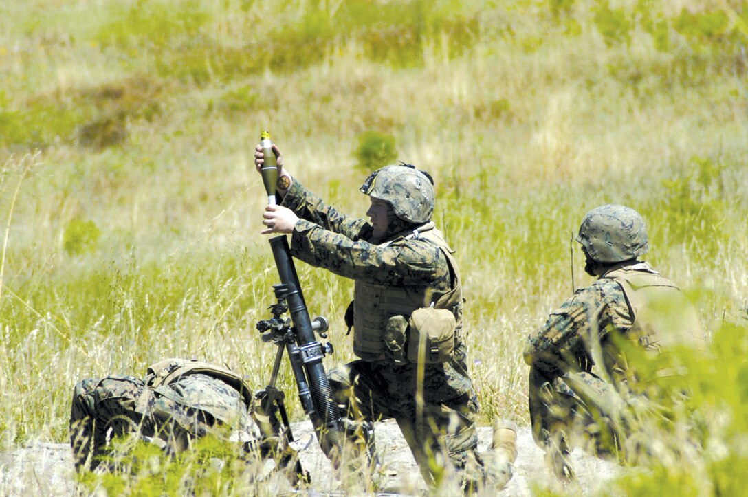 Lance Cpl. Josh P. Laine, 19, an assistant gunner with 2nd Battalion, 1st Marine Regiment, gives the preparatory warning, "hanging on one," before dropping a round into the mortar tube. The command lets the team know the round will be launched shortly. Each mortar is operated by three Marines.