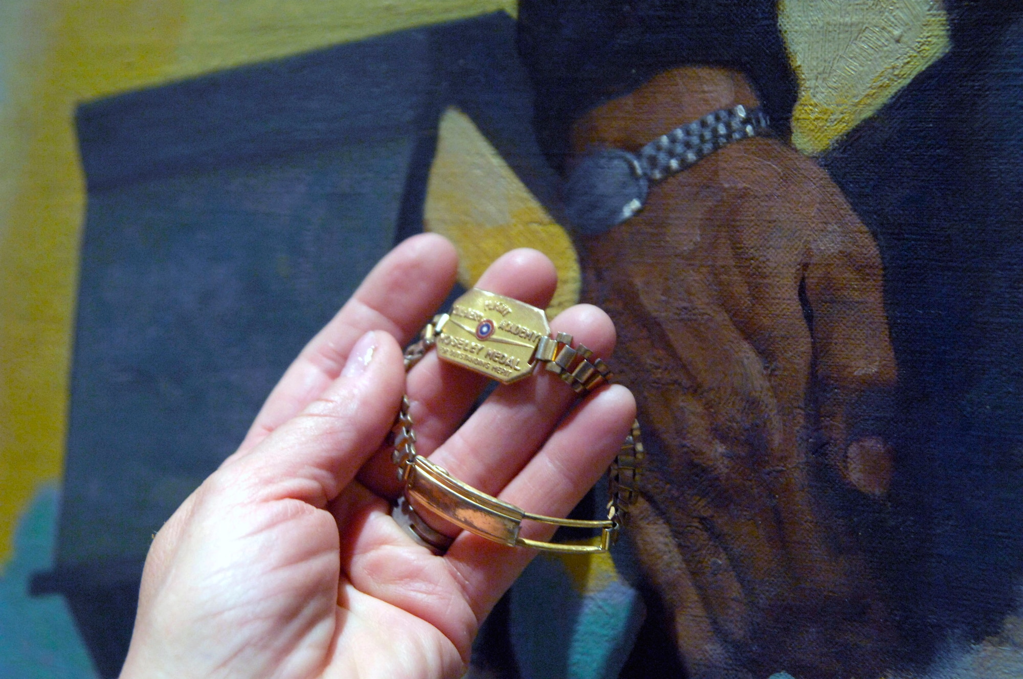Carol Ready holds the bracelet which her father, Capt. Thomas Wakeman, wore in the portrait displayed in the U.S. Air Force Band Headquarters building at Bolling Air Force Base, Washington, D.C. Captain Wakeman was a World War II veteran and B-26 Marauder pilot for the Army Air Forces. For the first time Mrs. Ready saw the original portrait, painted in 1944, during a visit to Washington.(U.S. Air Force photo/Tech. Sgt. Cohen A. Young)