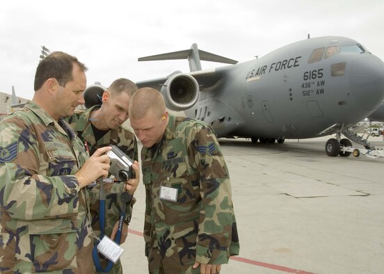 DOVER AIR FORCE BASE, Del. -- (Left to right) Tech. Sgt. Fred Potts, 712th Aircraft Maintenance Squadron, shares photos of Dover Air Force Base's first C-17 with Staff Sgt. Lance Moon and Senior Airman Adam Olson, 736th AMXS, May 21 at the Boeing C-17 production facility, Long Beach, Calif.  The Dover AFB maintenance technicians are in California to perform acceptance inspections on the aircraft before it's delivered to Dover AFB in a ceremony June 4. (Boeing photo/Gina Vanatter)
