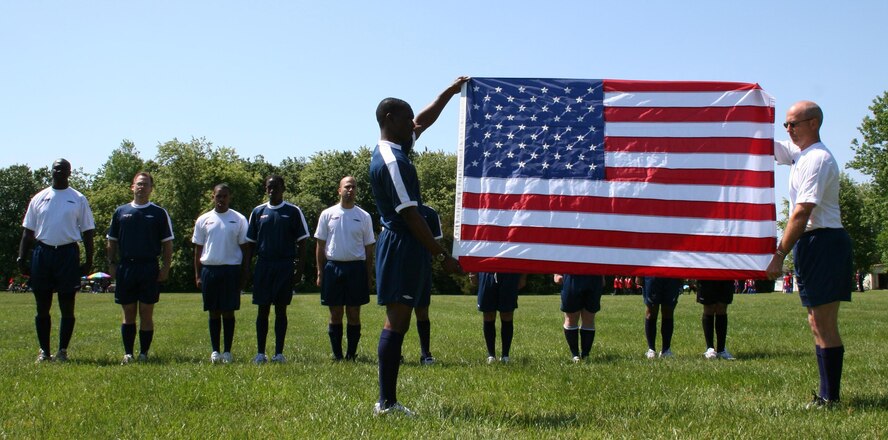 DOVER AIR FORCE BASE, Del. -- Senior Master Sgt. Bryan "Skip" Ford, 512th Maintenance Group quality assurance superintendent (right) and 1st Lt. Lyndell Miller, 436th Logistics Readiness Squadron, present an American flag as part of the opening ceremonies for Dover's Hispanic Soccer League. There are 22 Team Dover members playing for the varsity team. They compete against players from the local Dover area. 
